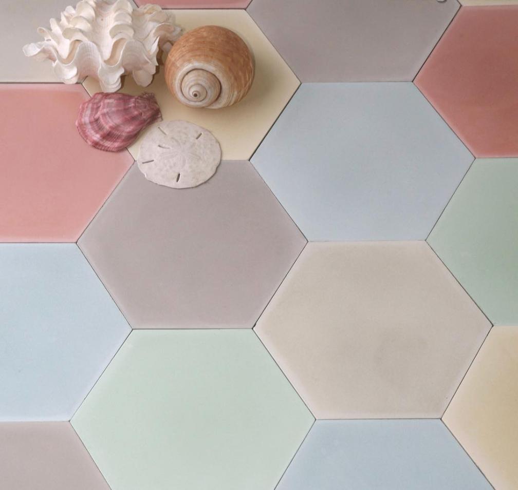 Seashells and a sand dollar rest on pastel-colored hexagonal tiles in shades of pink, cream, blue, green, and gray.