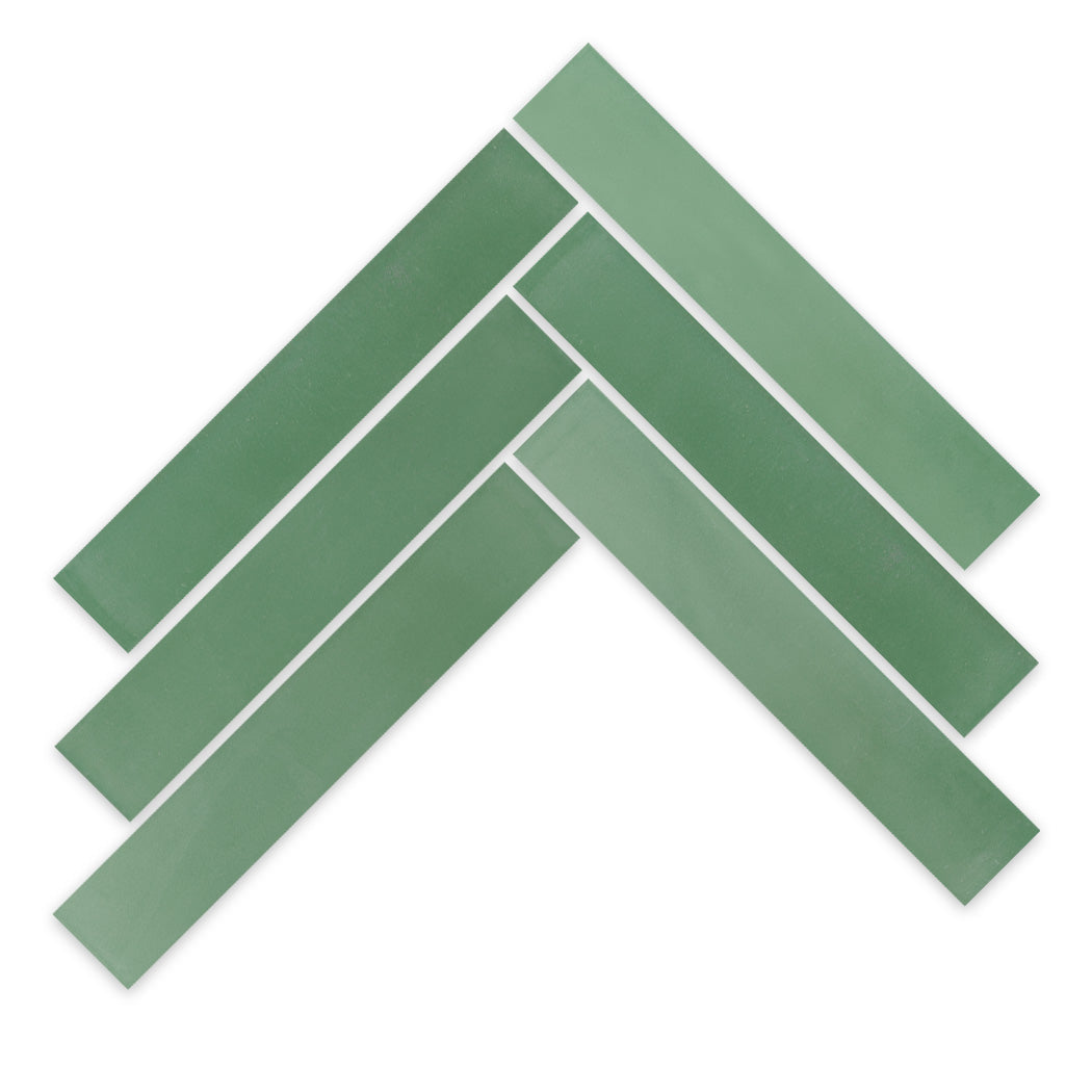 Five 2x12-Solid Gemstone Green tiles by New York Cement Tile in a chevron pattern on white.