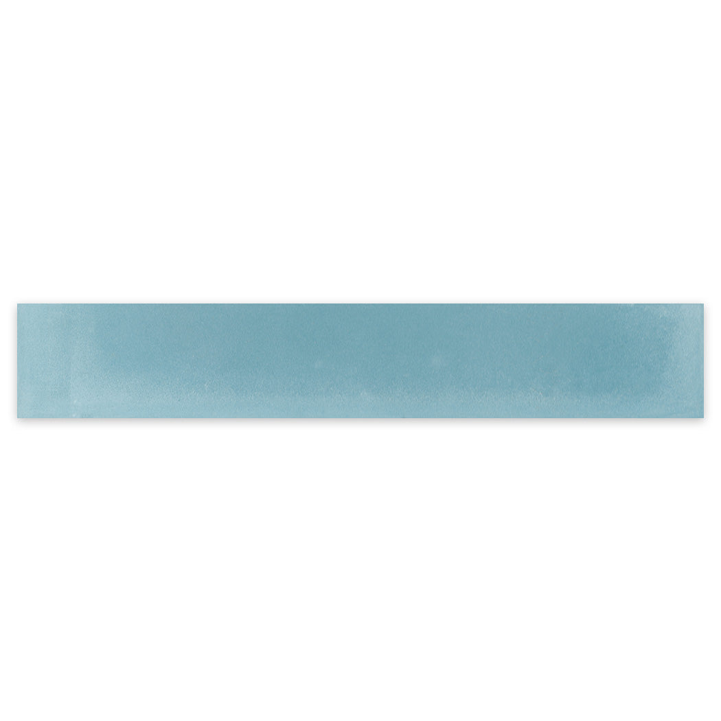 A long, rectangular 2X12-Solid Slate Sky tile sample by New York Cement Tile, light blue with smooth, shaded edges.