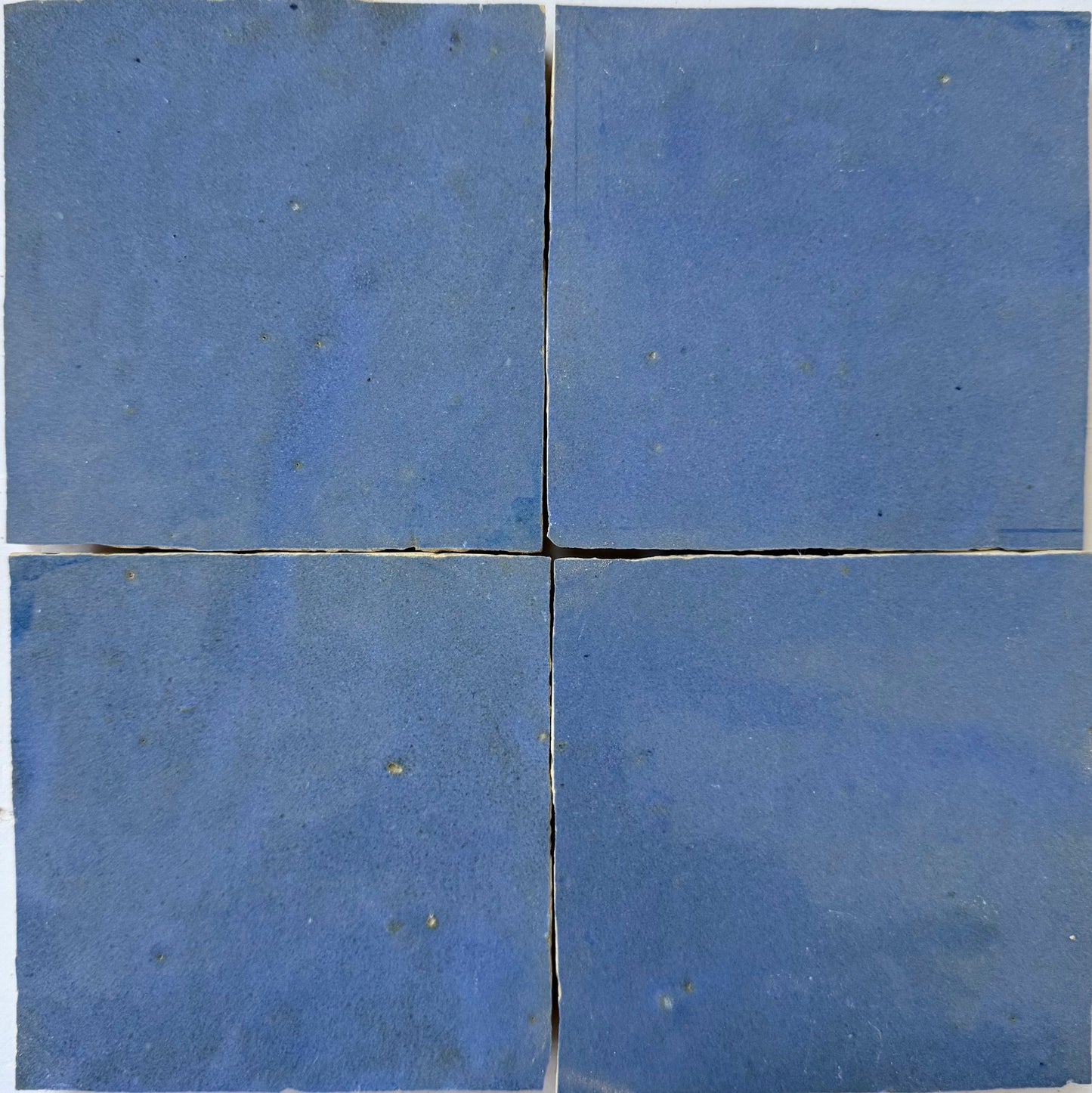 Four square blue Grape Extra Sample tiles by New York Cement Tile arranged in a grid with slight gaps and a simple design.