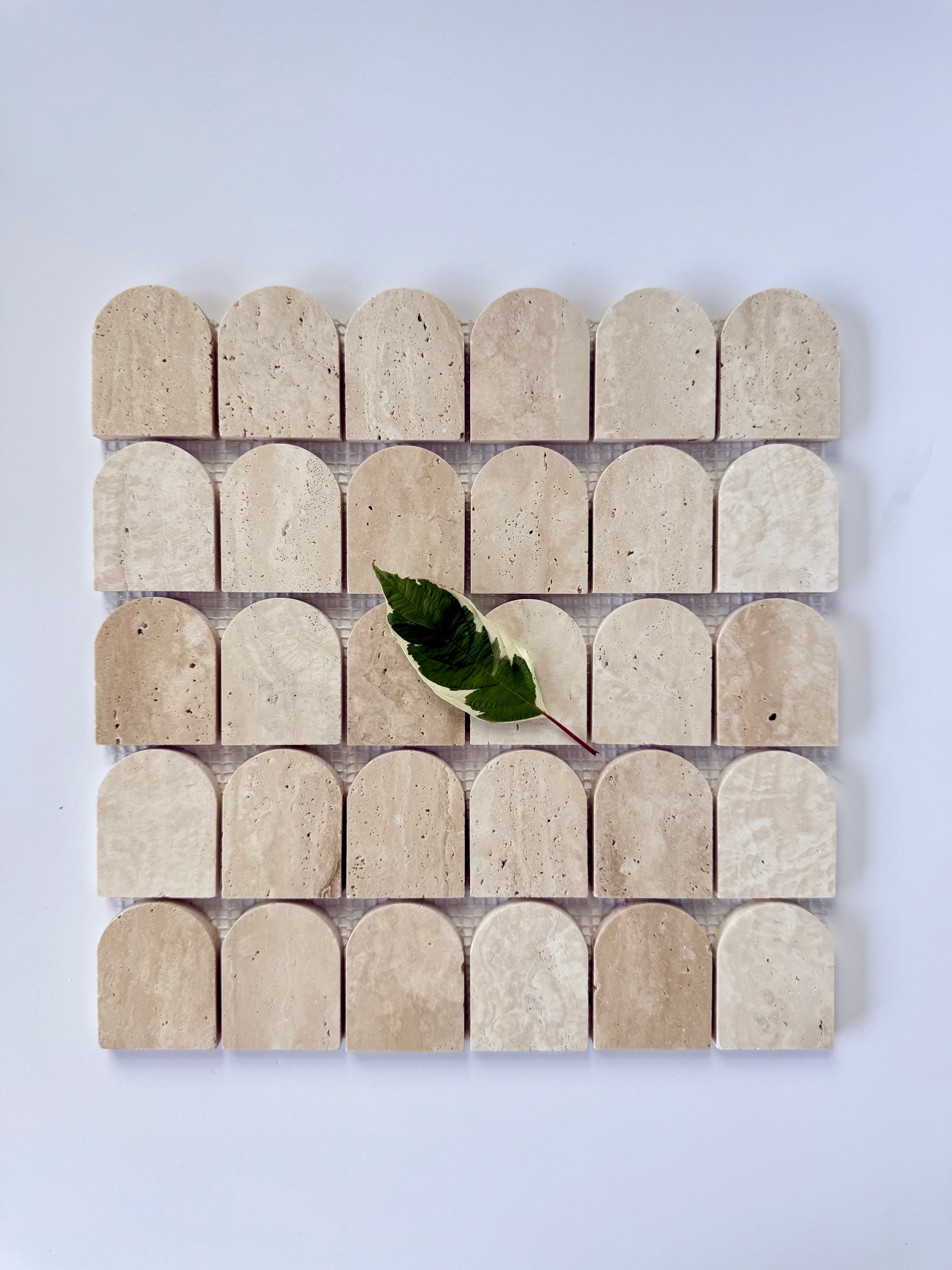 Scarpa I Travertine Arch Mosaic Marble Mesh by New York Cement Tile: four beige marble arches and a single green leaf motif.