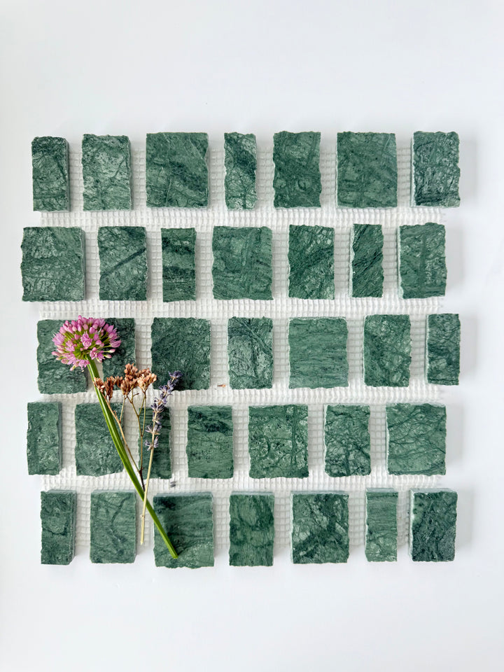 Scarpa I Emerald Mosaic Marble Mesh sample by New York Cement Tile, with green rectangular tiles in a grid and wildflowers on top.