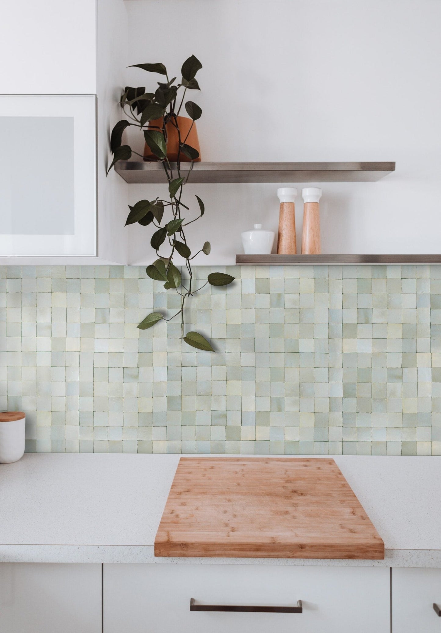 A kitchen counter with decor and shelves against a Mint Frost 2X2 backsplash by New York Cement Tile.