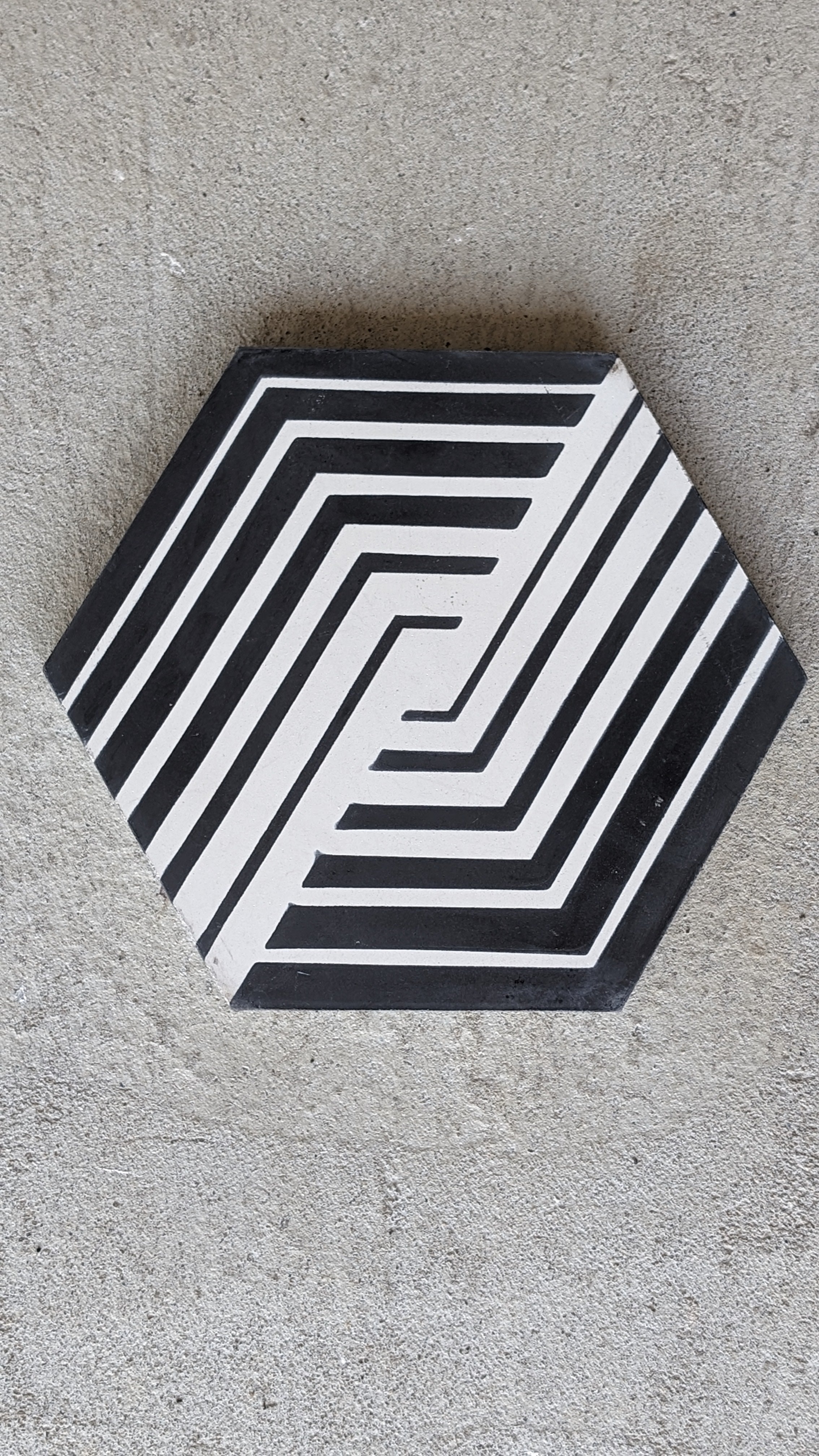 NL23-7 hexagon cement tiles by New York Cement Tile feature a geometric black & white stripe on gray concrete.