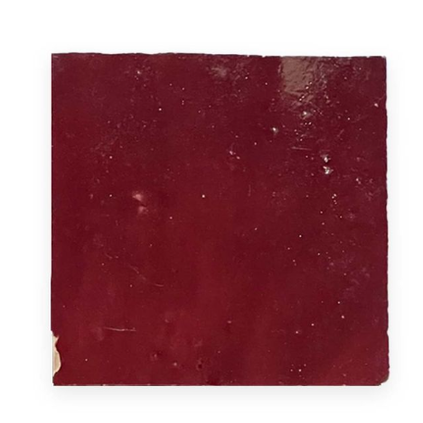 The Glazed Sangria by New York Cement Tile is a square, glossy deep red tile with a small chipped corner.