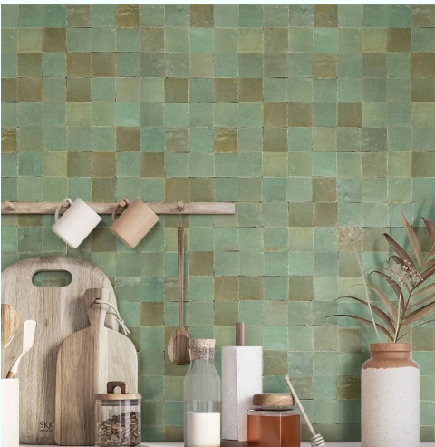 Kitchen scene with New York Cement Tile Leafy Green 2X2 tiles, wooden utensils, cutting boards, bottles, and a plant.