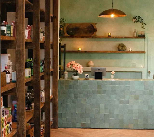 Cozy shop with wooden shelves, soft lighting, and an Olive Grove Zellige tile front desk by New York Cement Tile.