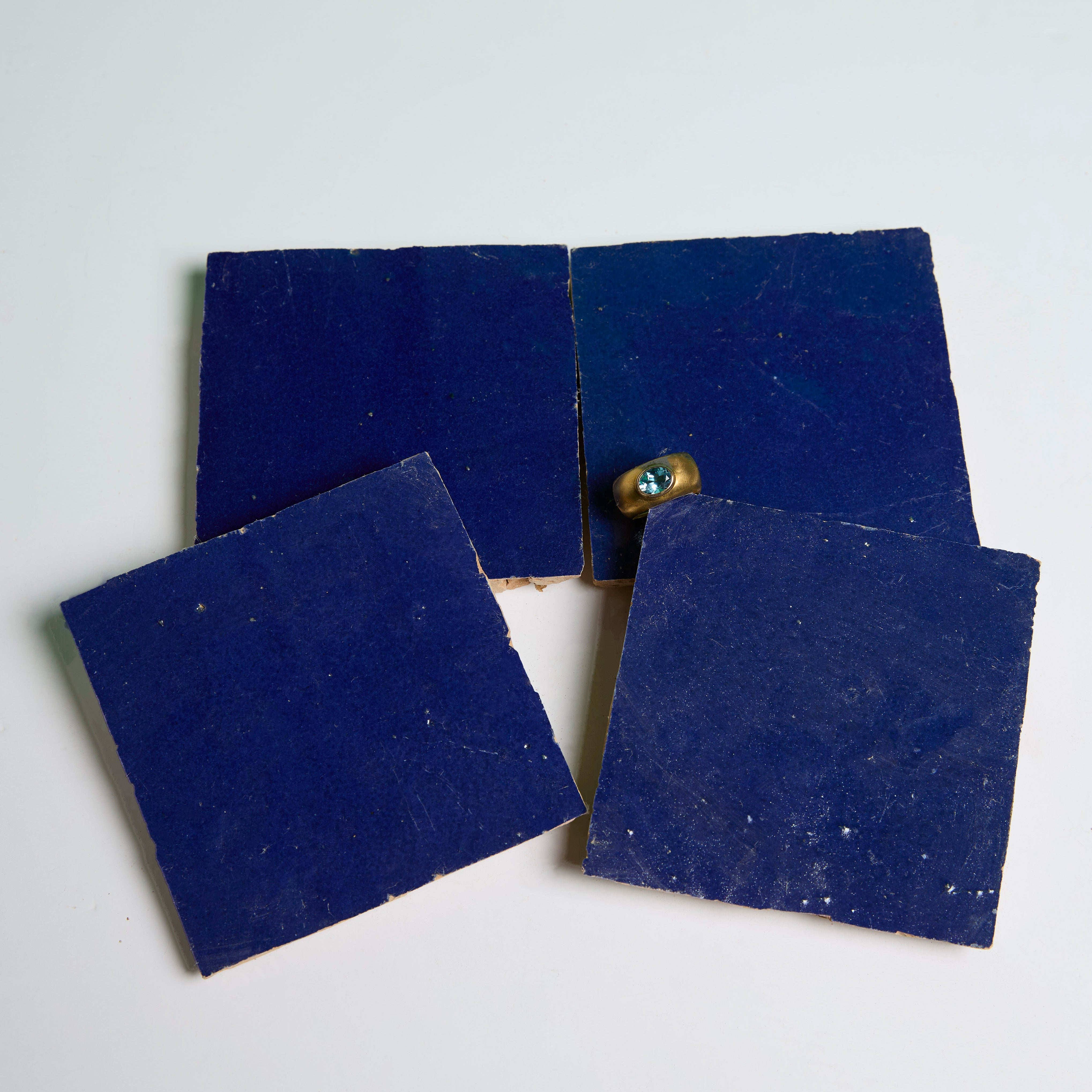 Four Navy Depths tiles by New York Cement Tile in a rough square on white, with a small bolt on one tile.