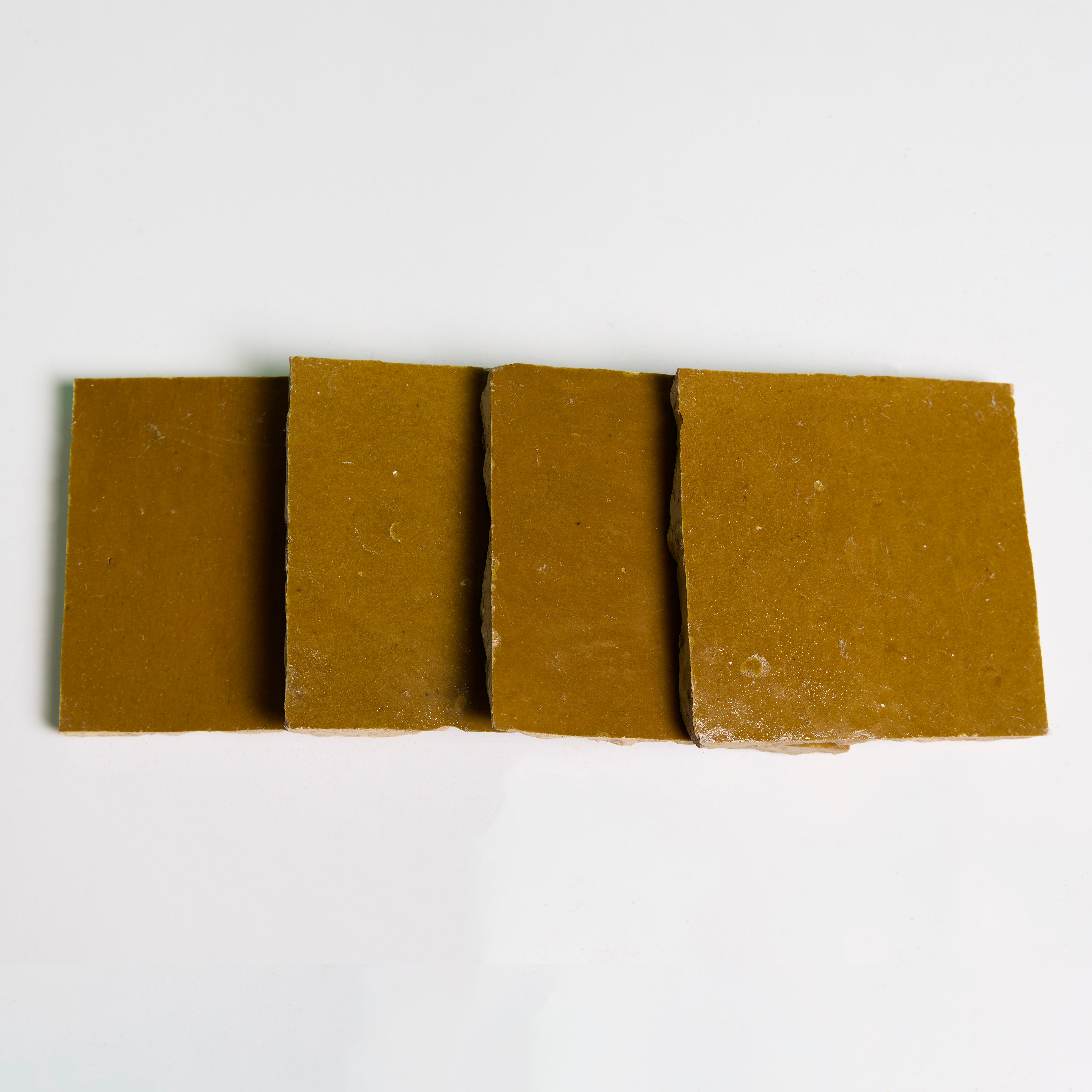 Four Caramel Glazed soaps by New York Cement Tile, arranged in a row like handcrafted tiles on a white background.