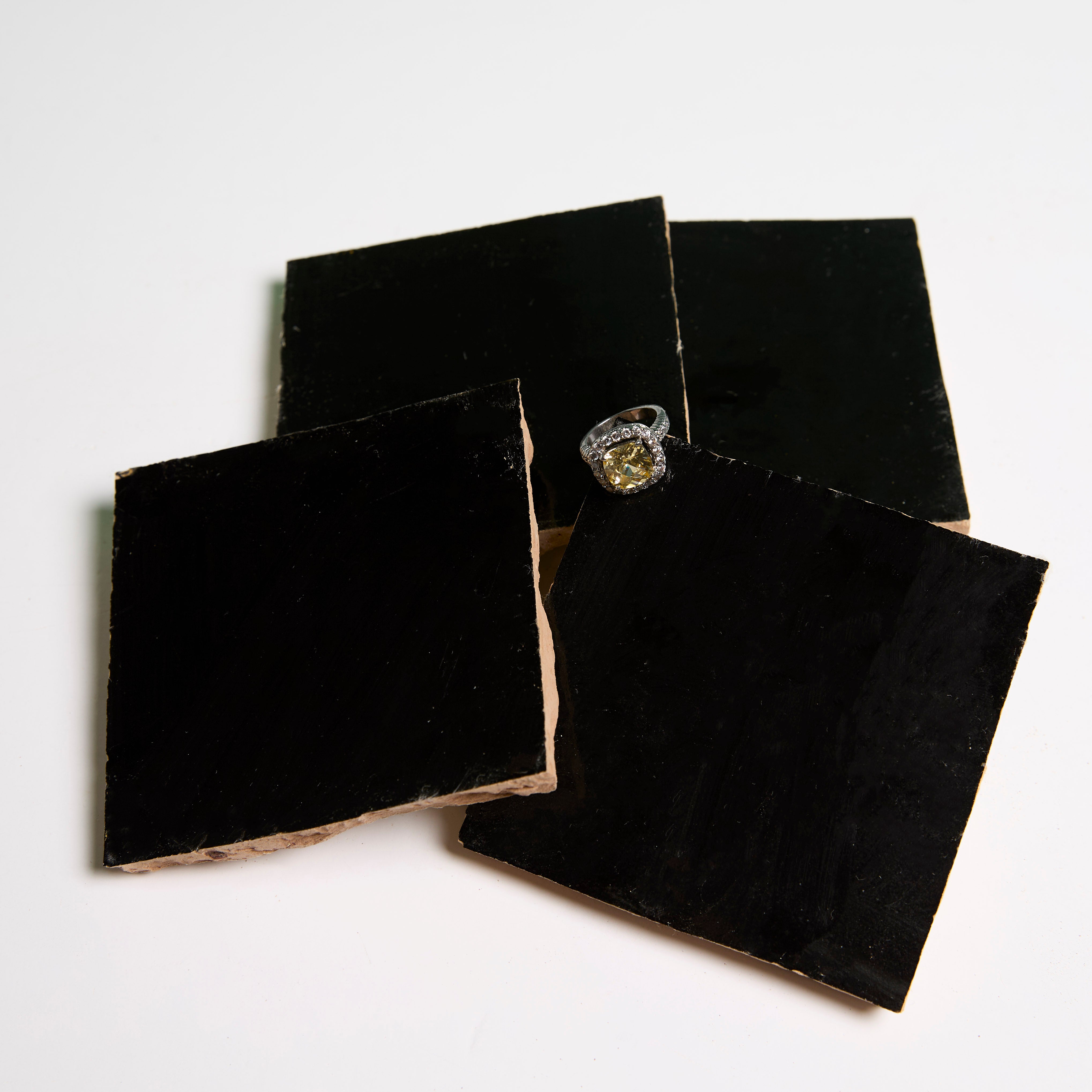 Three New York Cement Tile Black Onyx tiles and one with a ring on top are arranged on a white surface.