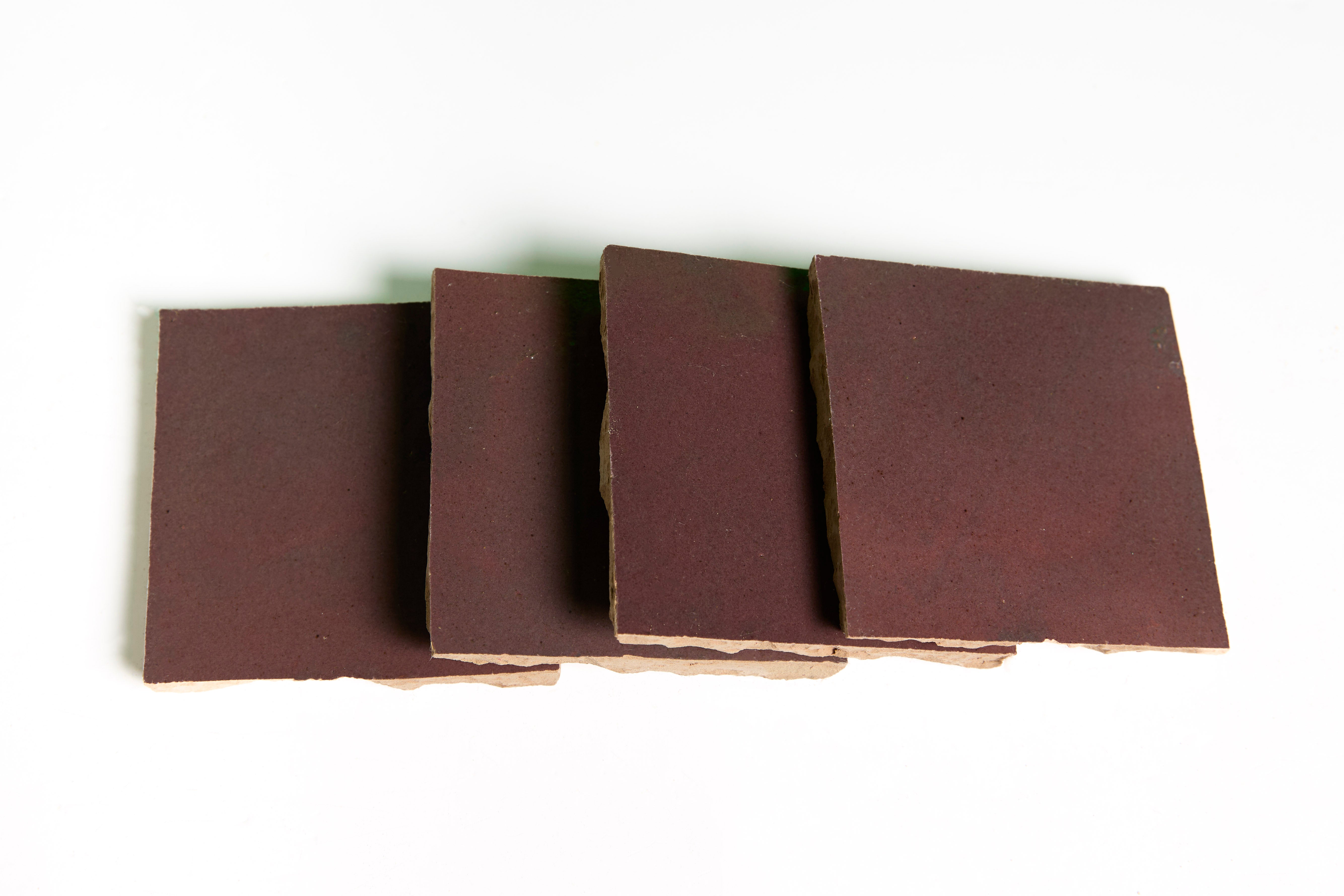 Four brown, square Thistle tiles by New York Cement Tile are stacked in a slightly overlapping row on white.