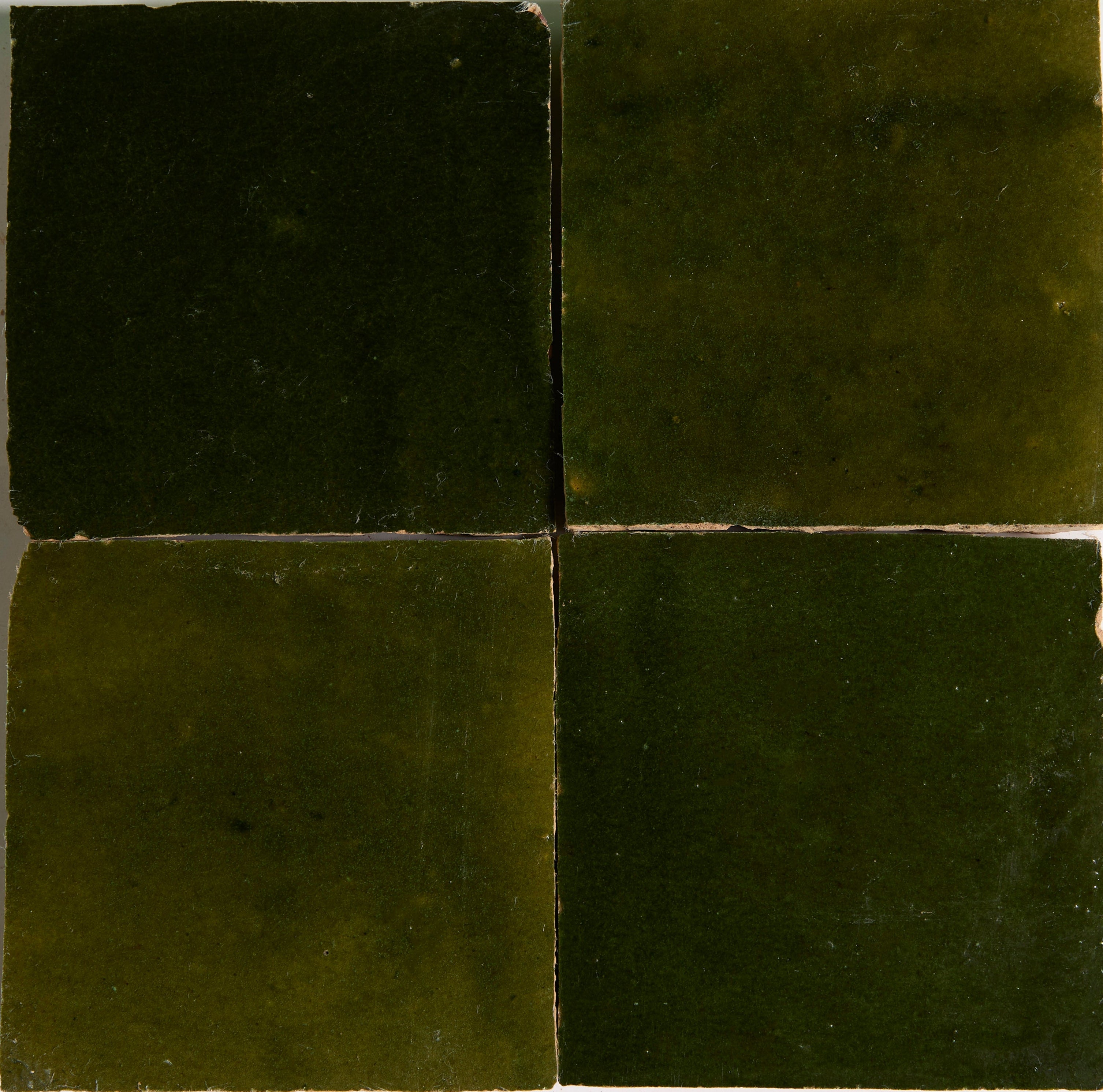 Four Moss Green tiles by New York Cement Tile in a 2x2 grid, showcasing seams and artisanal craftsmanship.