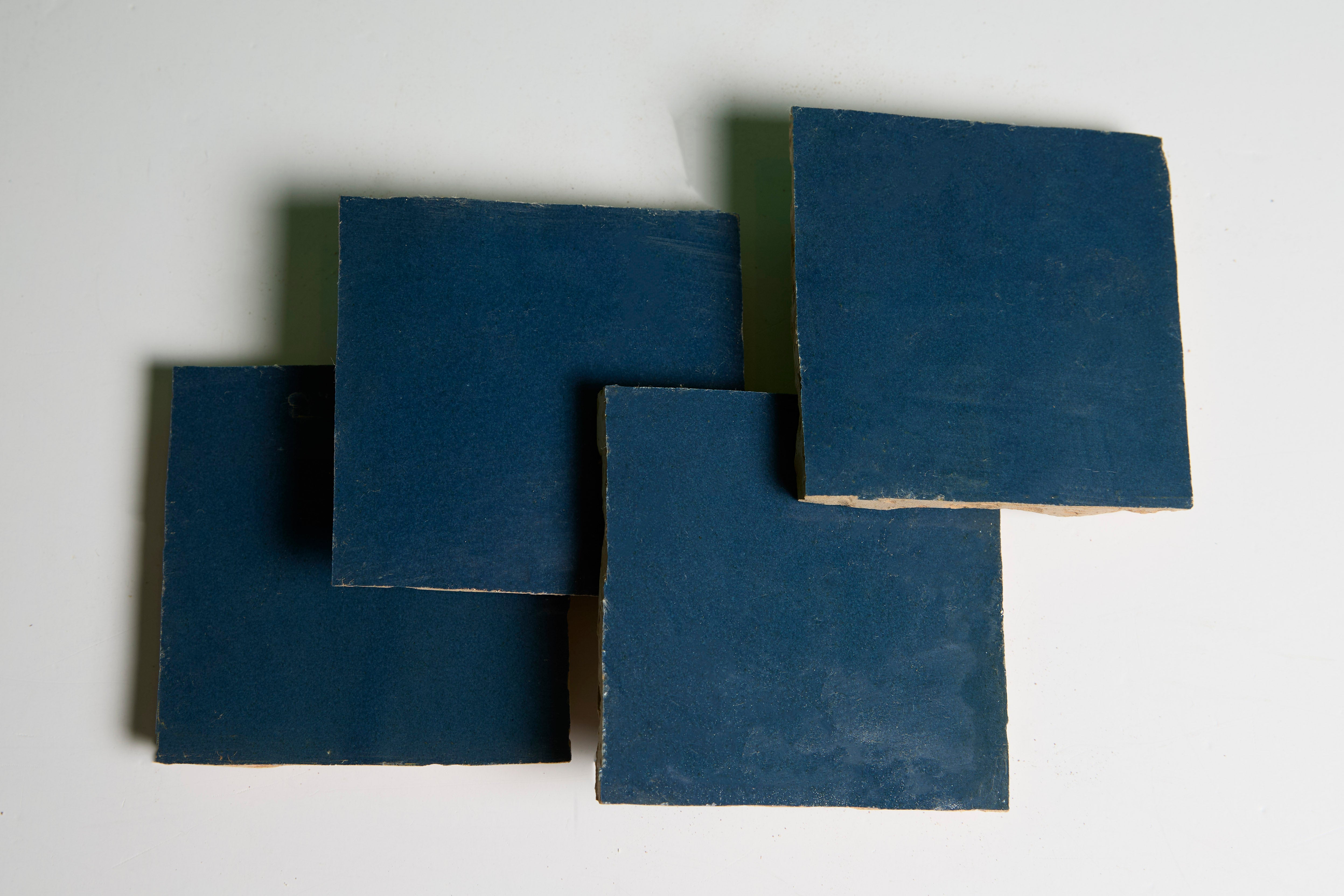 Four Sea Breeze tiles by New York Cement Tile overlap slightly, forming a blue square pattern on a white surface.