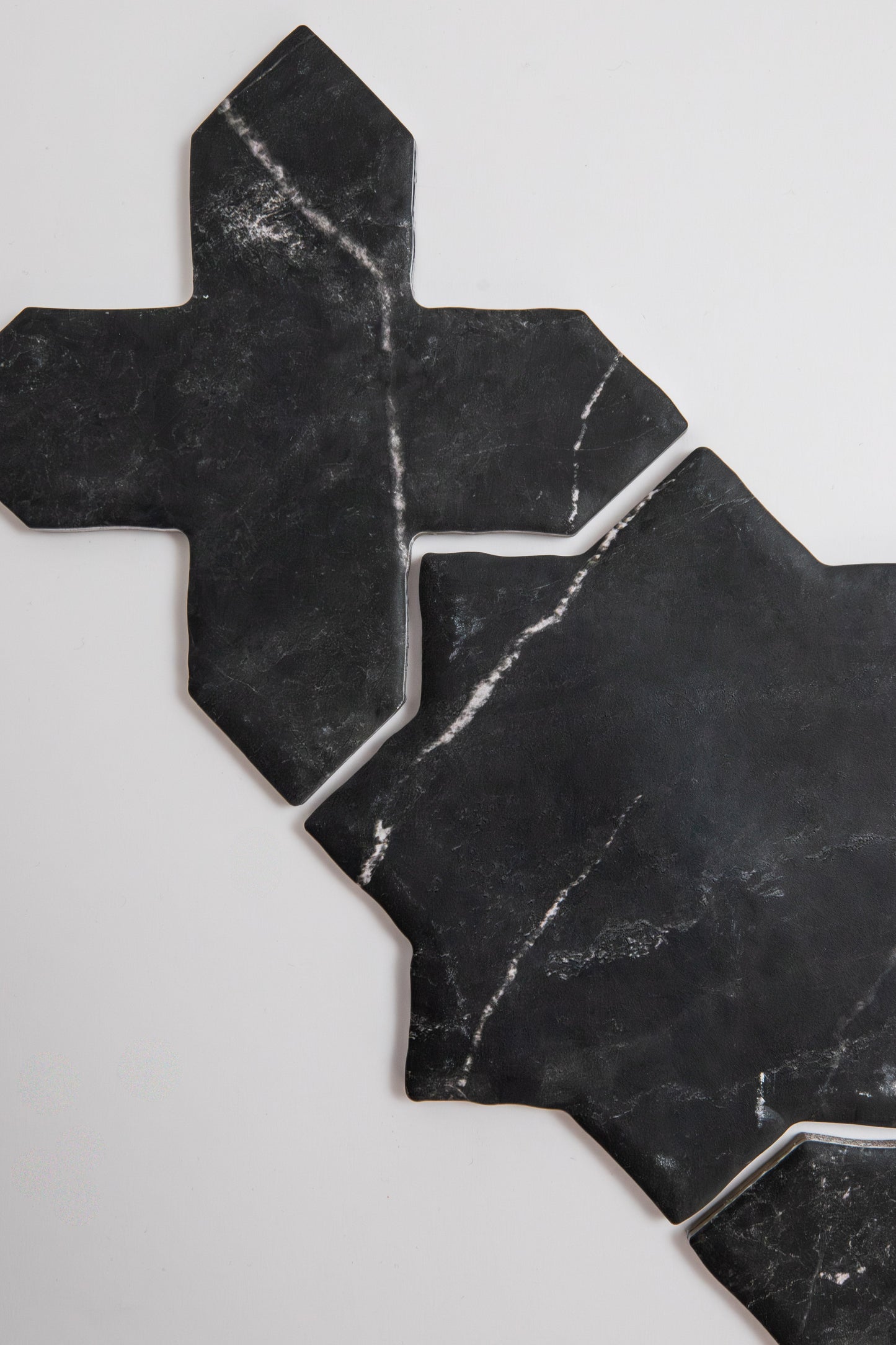 Two Black Marble, Extra Sample tiles by Tosca feature geometric cross shapes on a white background.