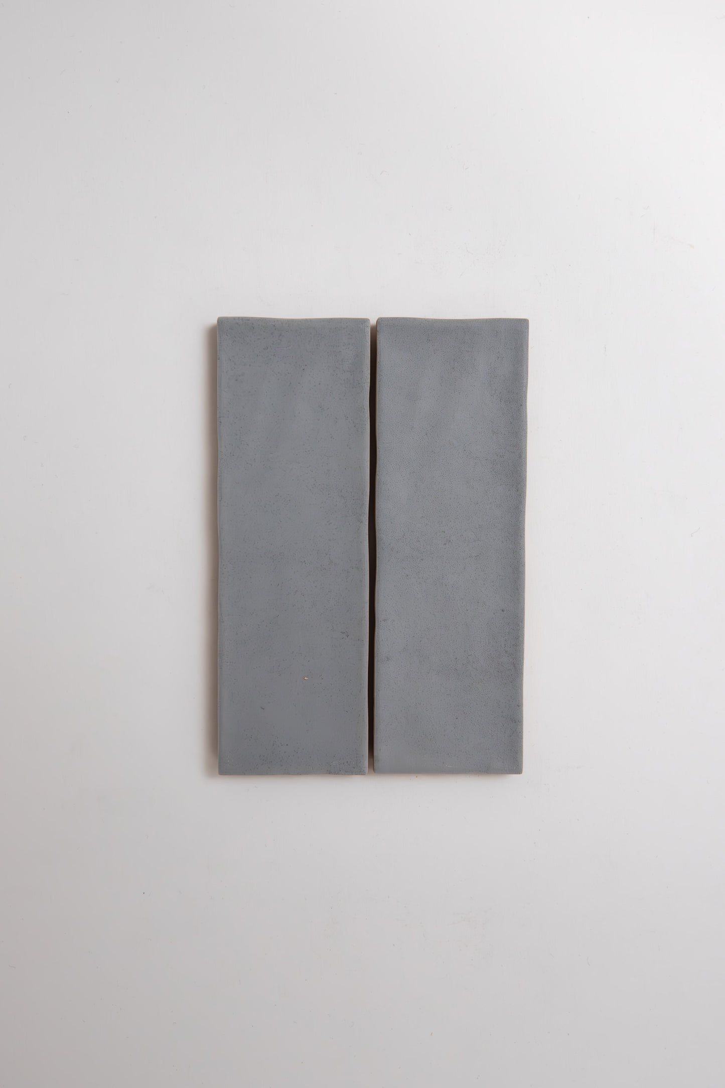 Two rectangular Bourton Dark Blue tiles by Cottage Ivy are mounted side by side on a white wall with a narrow gap.