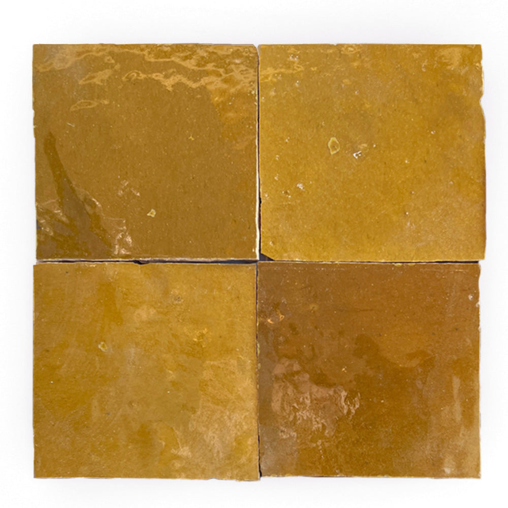 Four square, caramel-glazed Zellige tiles by New York Cement Tile are arranged in a grid on a white background.