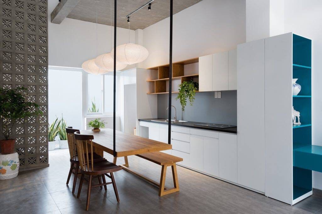 Modern kitchen featuring Beeza Sample tiles by New York Cement Tile, wooden table, white cabinets, and open shelves.