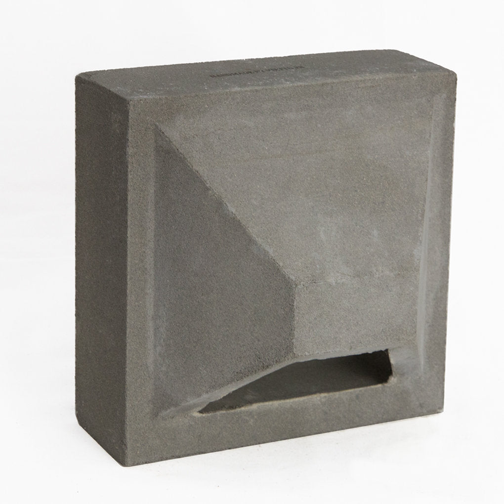 The Hawa Sample by New York Cement Tile is a square gray concrete block with an angular indentation for decorative partitions.