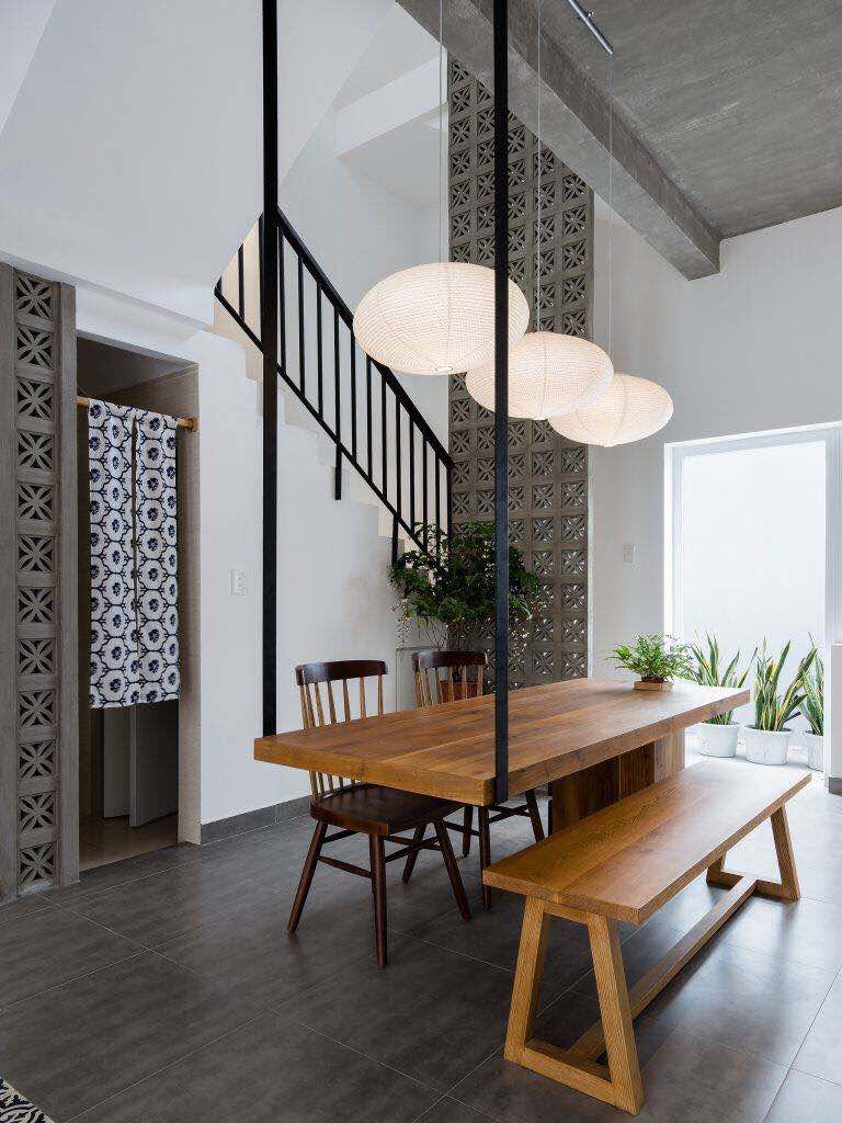 Modern dining area with a Beeza Sample wood table from New York Cement Tile, mid-century chairs, and three pendants.