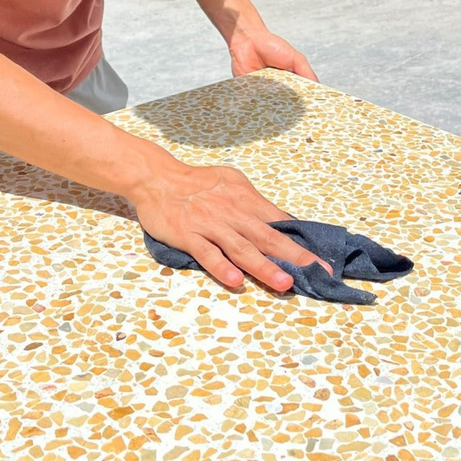 Someone cleans a TERRAZZO 24X24-Cane sample by New York Cement Tile, revealing its stunning look in bright sunlight.