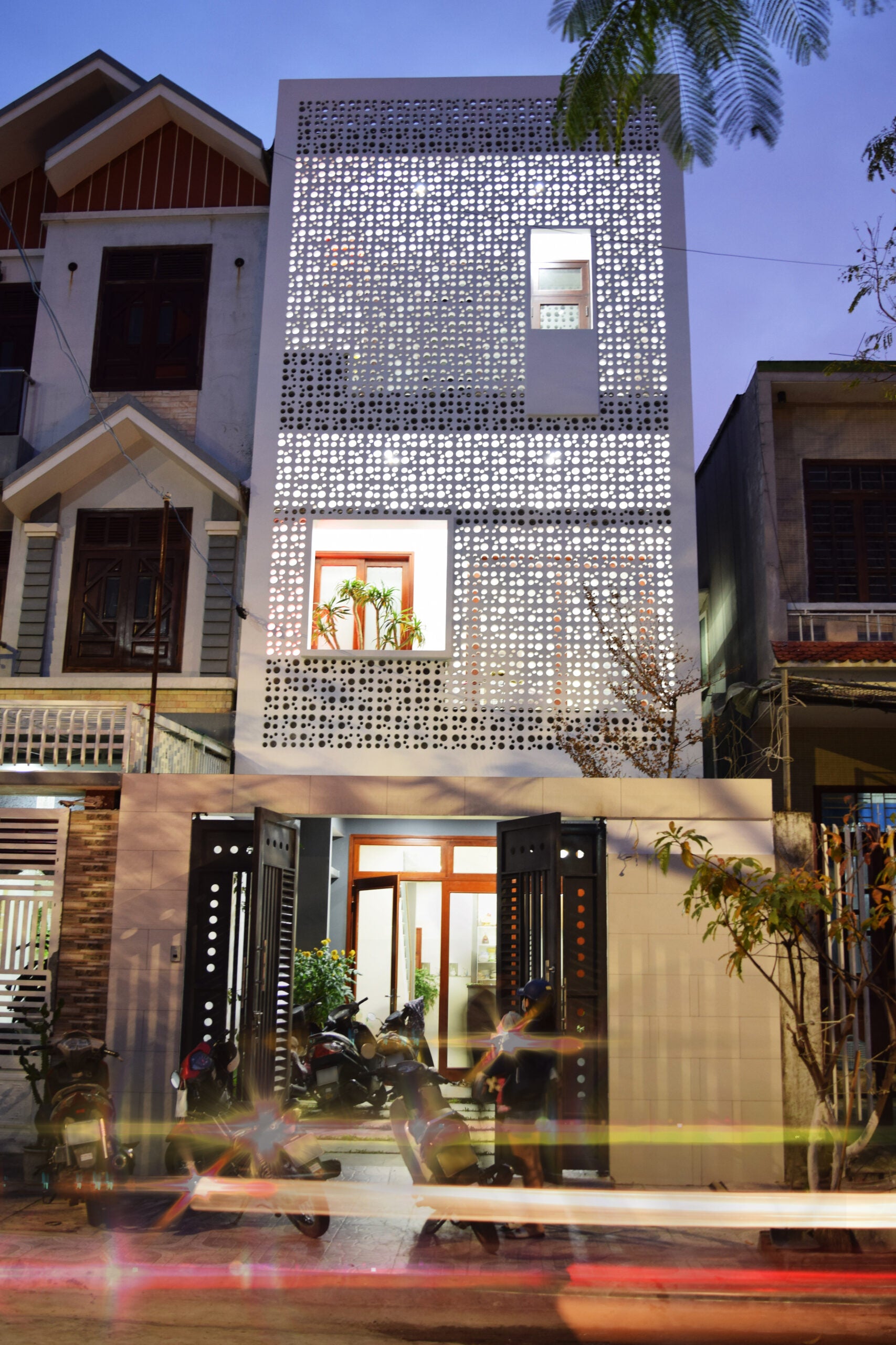Jami by New York Cement Tile: modern three-story house with breeze blocks, white facade, and dusk lighting.