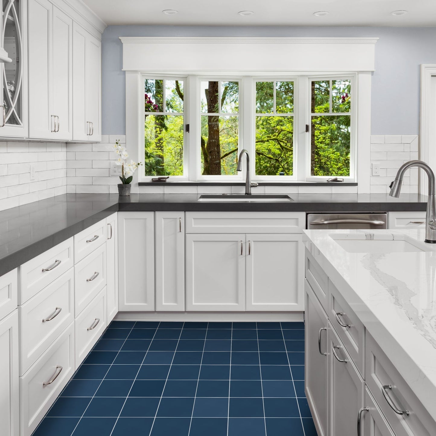 Modern white kitchen featuring New York Cement Tile 4412-Solid 8x8 navy tiles, large windows, and green views.