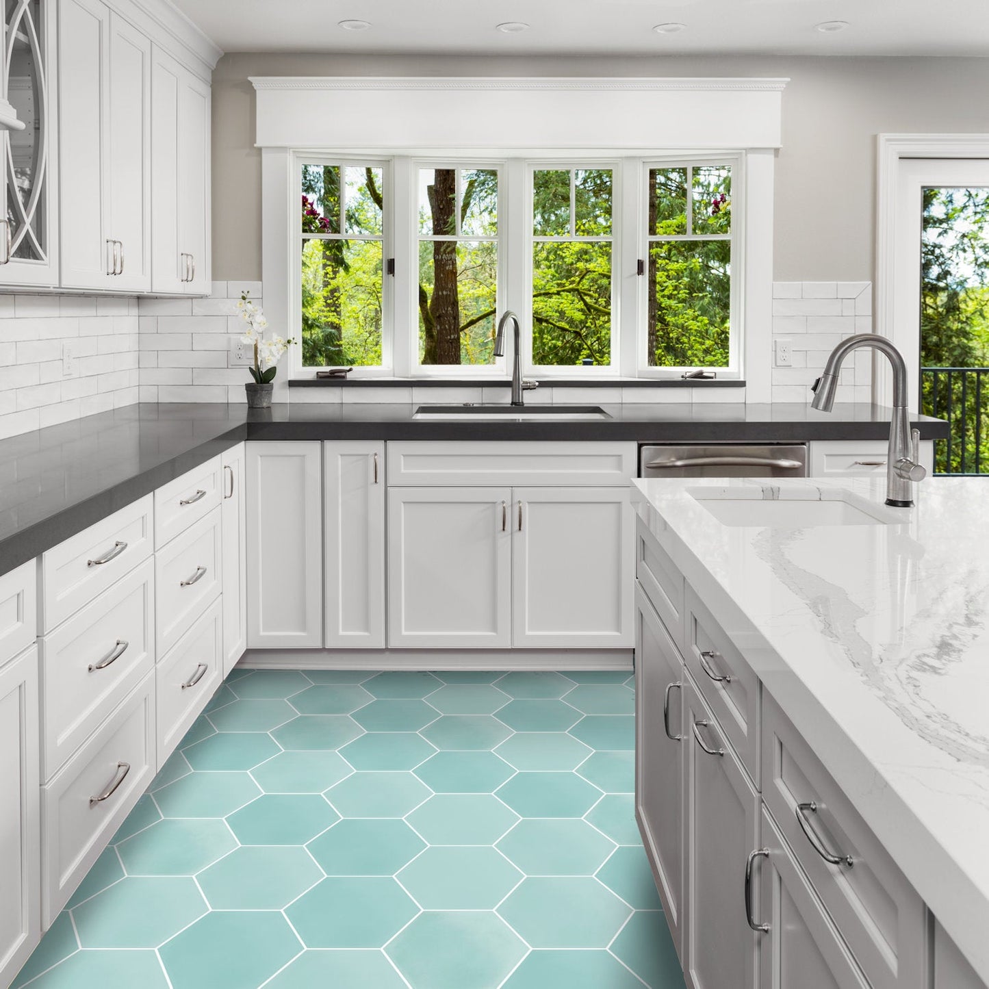 Modern kitchen with white cabinets, dark counters, NH23-3309 teal hex tiles by New York Cement Tile, and large windows.