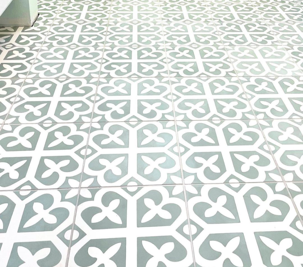 Patterned floor tiles with a repeating design of white clover shapes on a light green background.