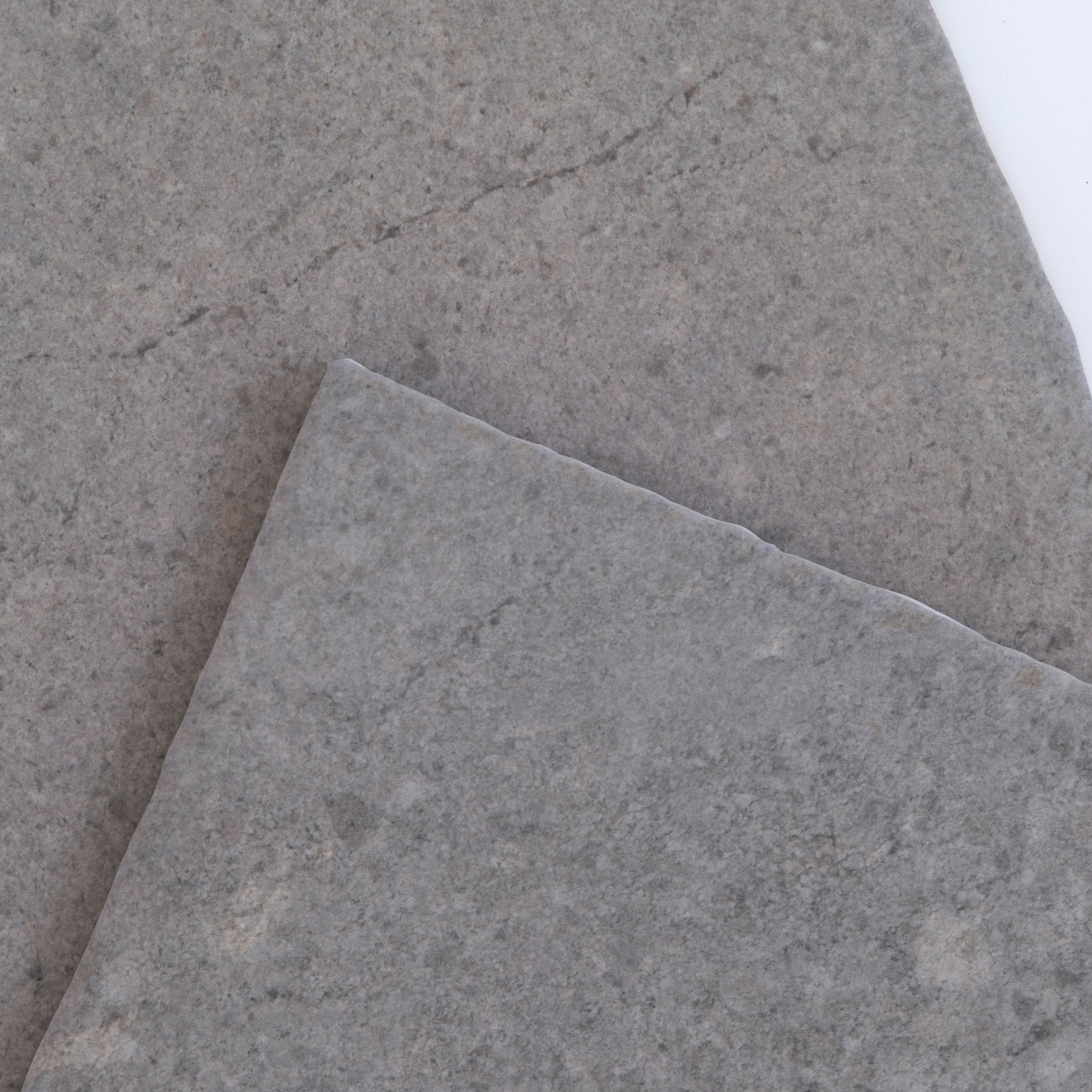 The Toba Basilica R11 by New York Cement Tile is a square gray stone tile with a rough texture on a white background.
