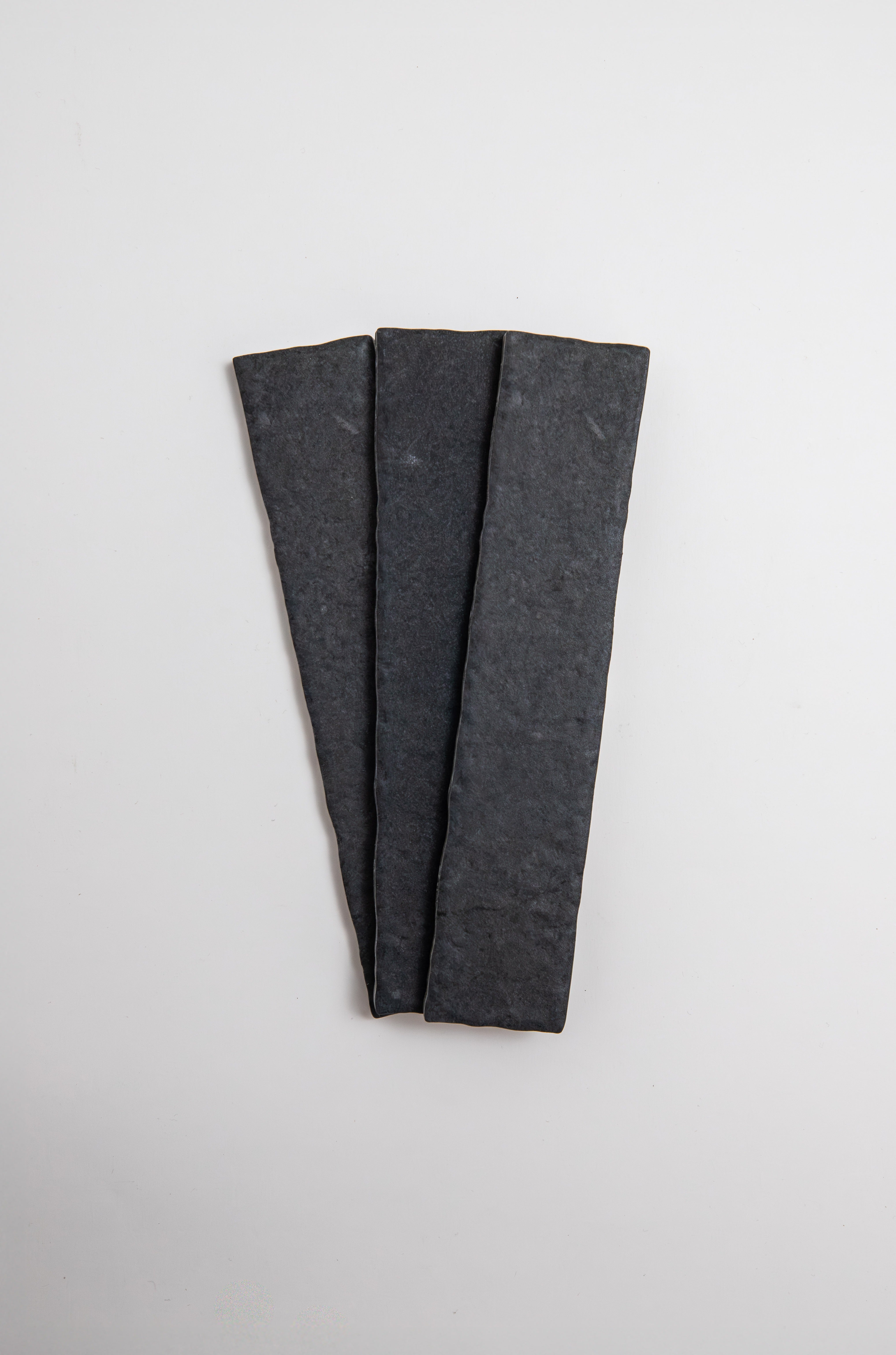 Three Toba Black R11 sample tiles by Toba arranged in a fan shape on a plain white background.