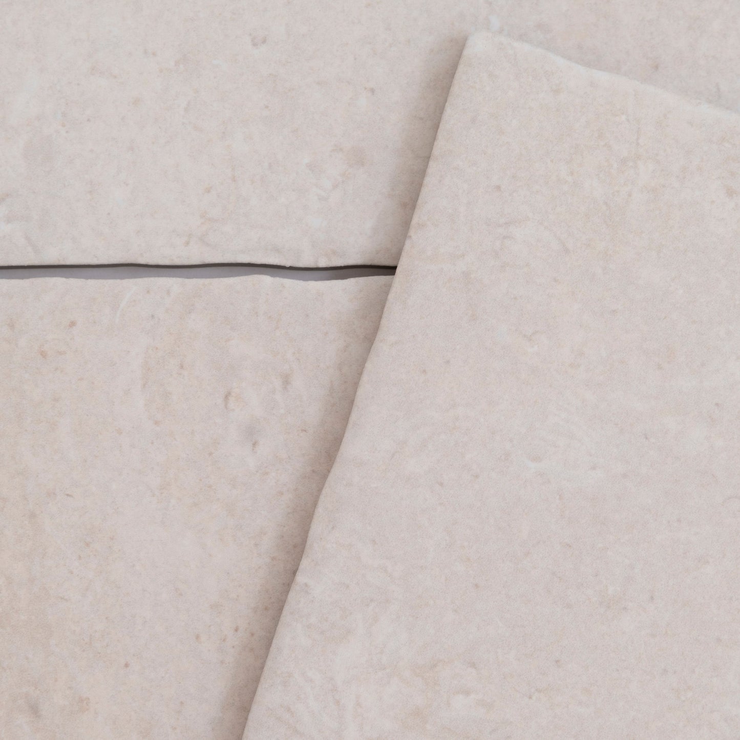 Close-up of Toba Ivory R11 tiles by Toba, in light beige with a visible grout line and slight tile overlap.