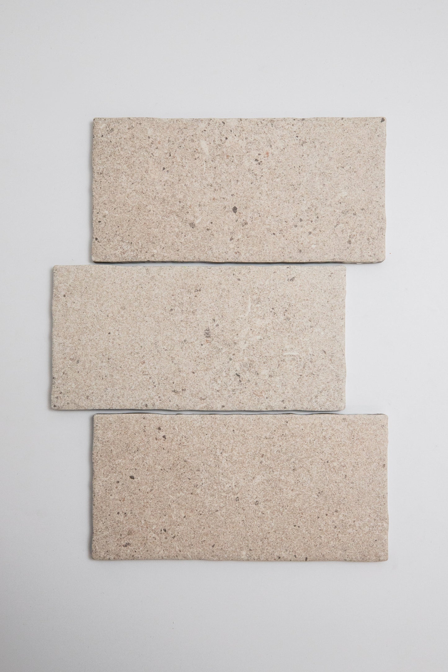 Three Toba Taupe R11, Sample tiles by Toba are arranged vertically in a staggered stack on a light gray background.