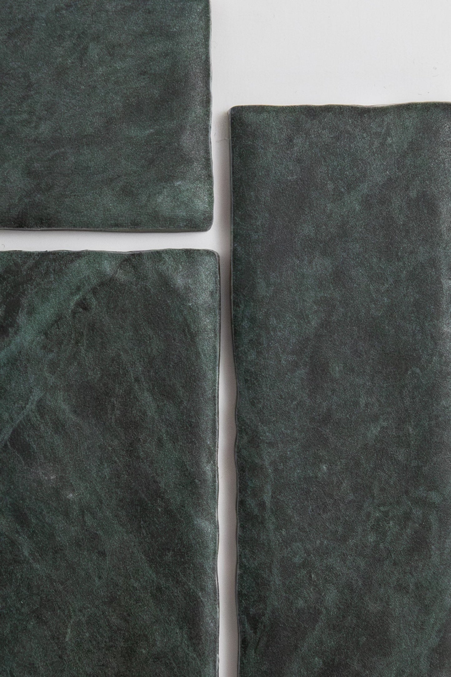Four Verde Tia tiles by Tosca, dark green and rectangular with a rough texture, arranged on a white background.