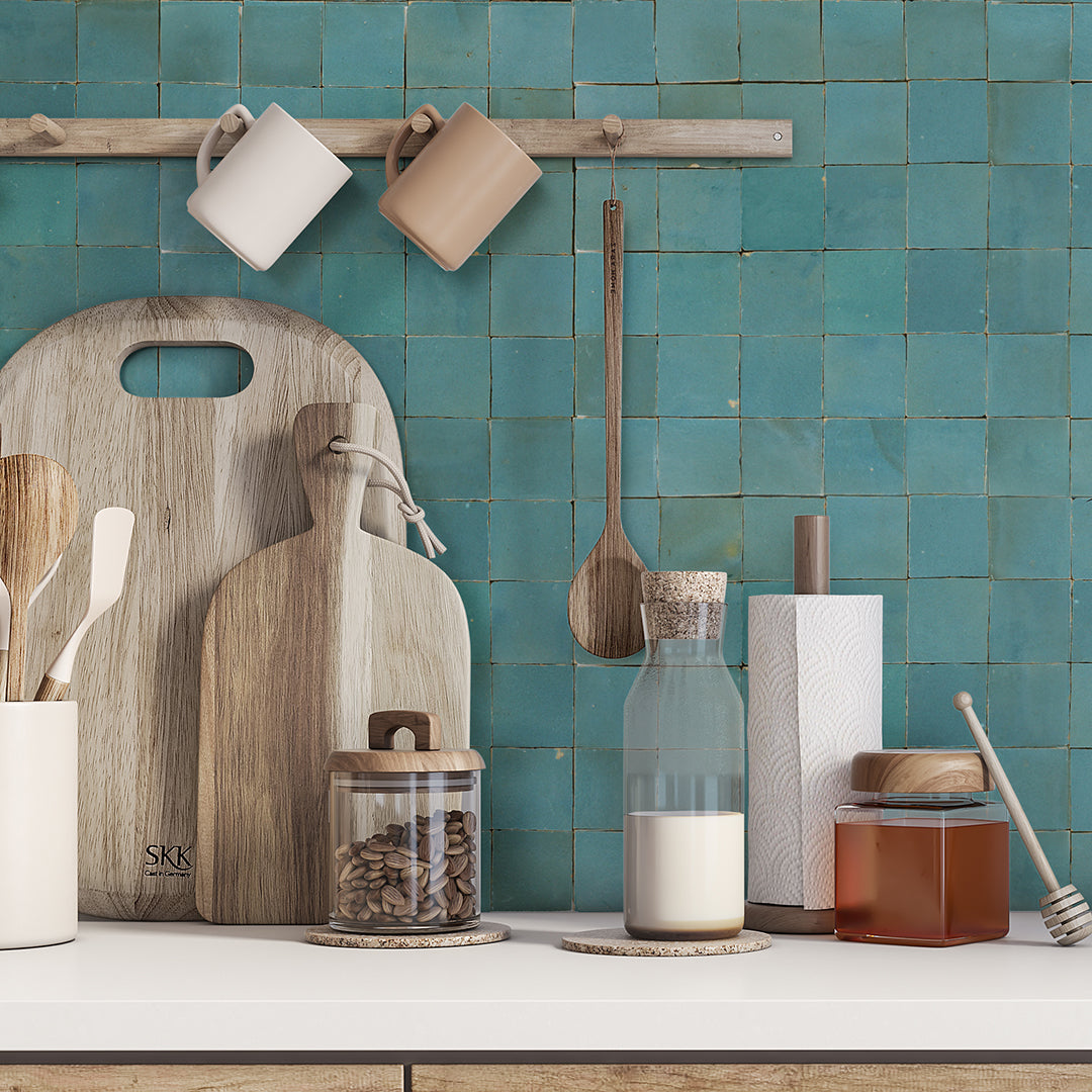 Water line tile samples by New York Cement Tile create a striking backsplash behind kitchen utensils and jars on the counter.