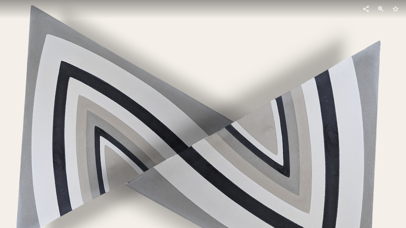 Two triangular tiles overlap, each featuring concentric curved stripes in shades of gray, black, and beige, forming abstract, geometric patterns on a light background. Shadows are cast behind the tiles.