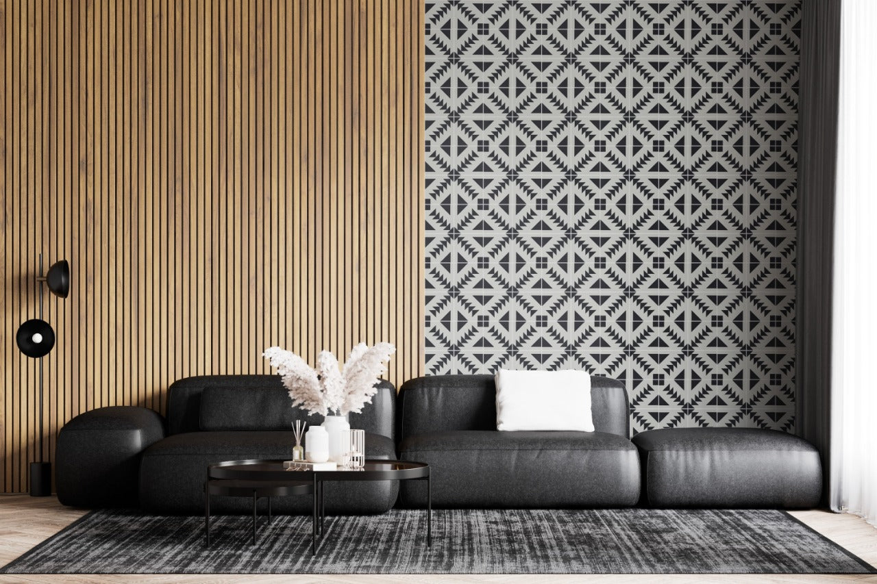 Modern living room with a black sofa, geometric accent wall, wood paneling, round coffee table, and neutral rug.