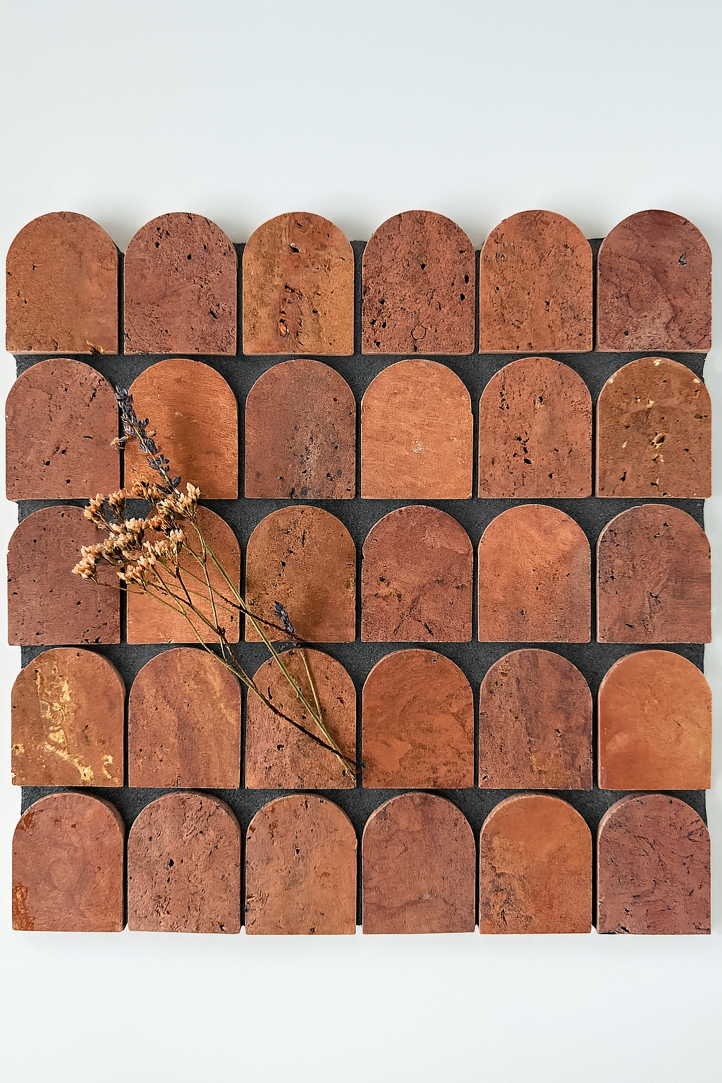 Scarpa I Red Travertine Arch Mosaic by New York Cement Tile with dried lavender flowers arranged diagonally on the tiles.