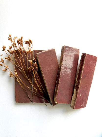 Four Thistle (2x6) tiles by New York Cement Tile arranged diagonally with brown soap bars and dried flowers.