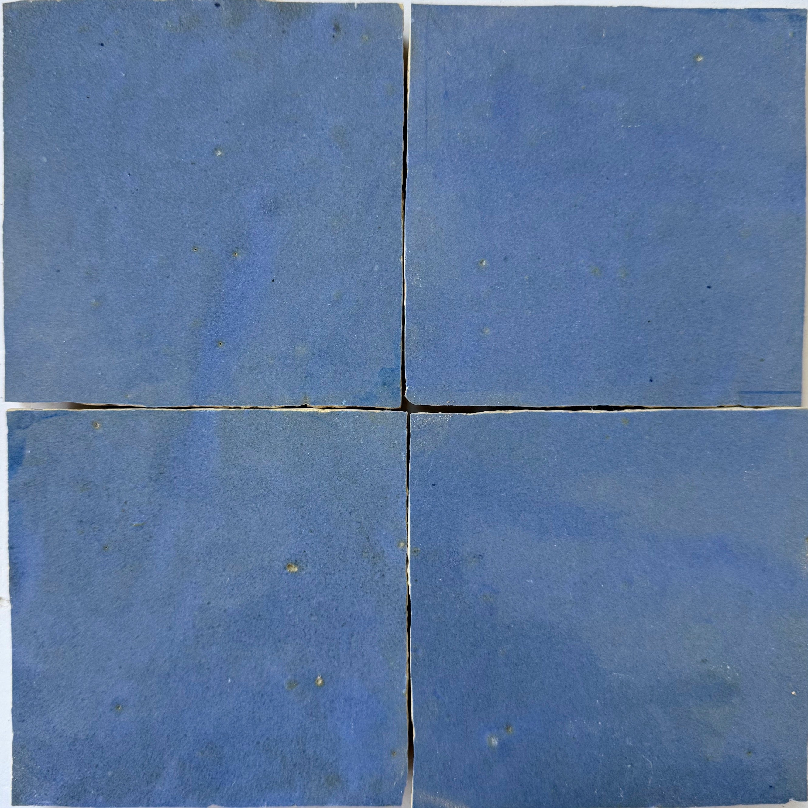 Four square blue "Grape" tiles by New York Cement Tile arranged in a grid with slight gaps between them.