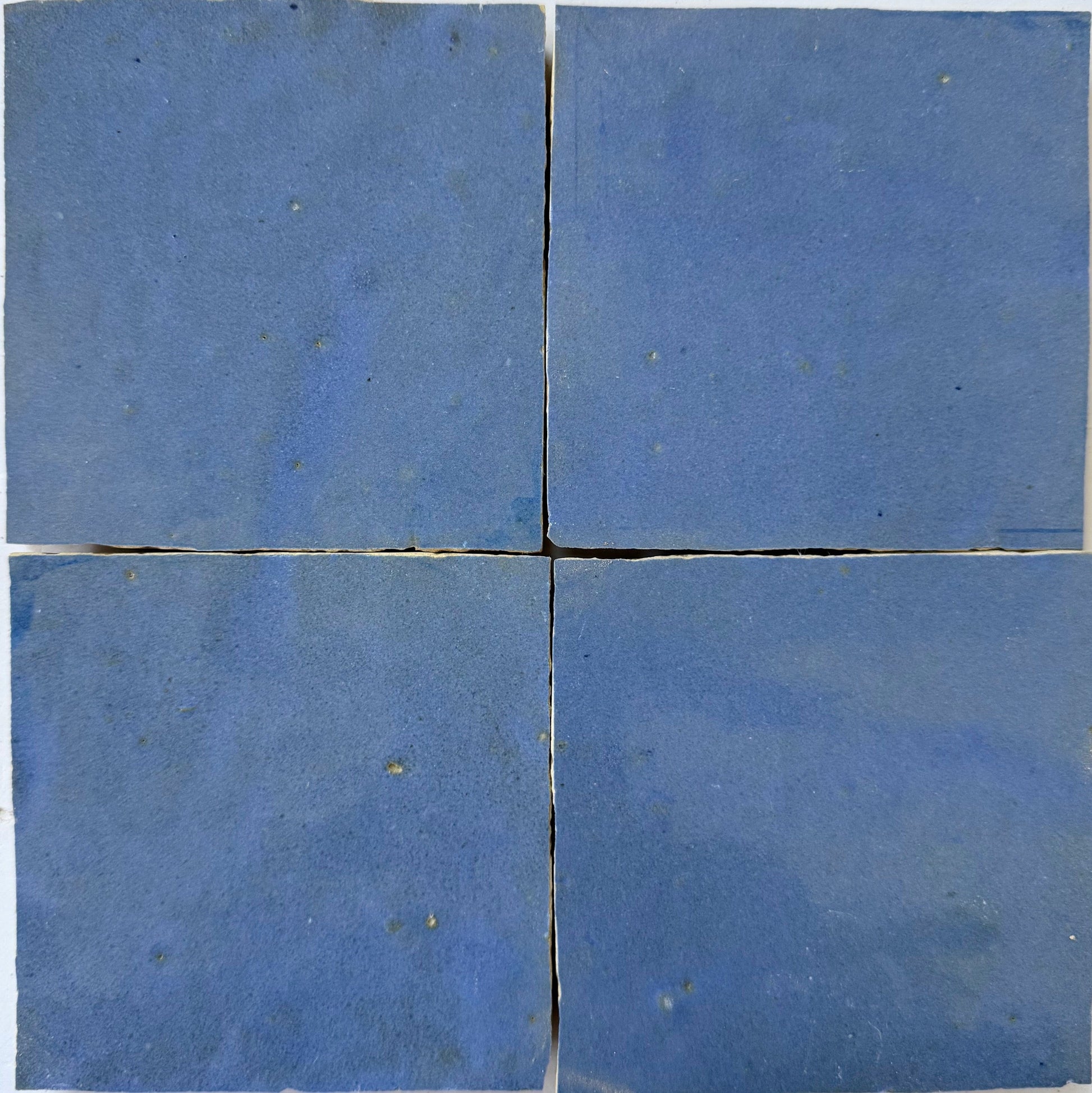 Four square blue Grape Extra Sample tiles by New York Cement Tile arranged in a grid with slight gaps and a simple design.