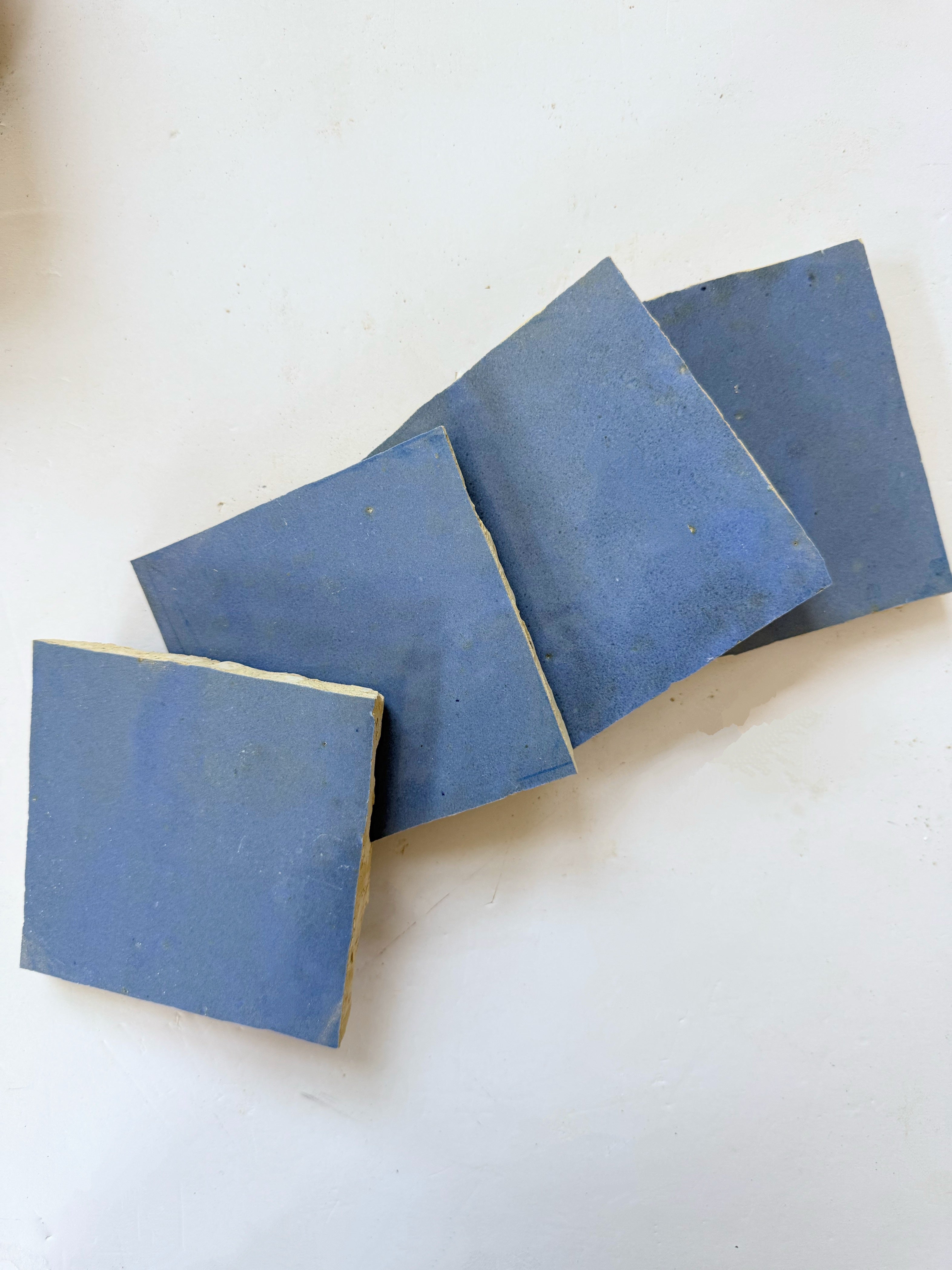 Four Grape tiles by New York Cement Tile are loosely arranged in a diagonal line on a white surface.