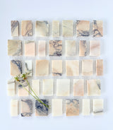 Scarpa I Mountain Mosaic Marble Mesh by New York Cement Tile in pink, white & gray, shown with two white flowers on top.