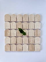 Scarpa I Travertine Arch Mosaic Marble Mesh by New York Cement Tile: four beige marble arches and a single green leaf motif.