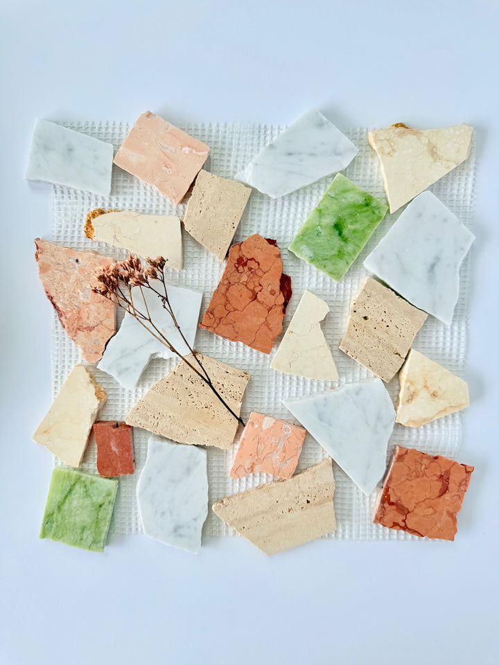 Candy - Puzzle stone tiles by New York Cement Tile arranged on a white grid, accented with dried flowers.