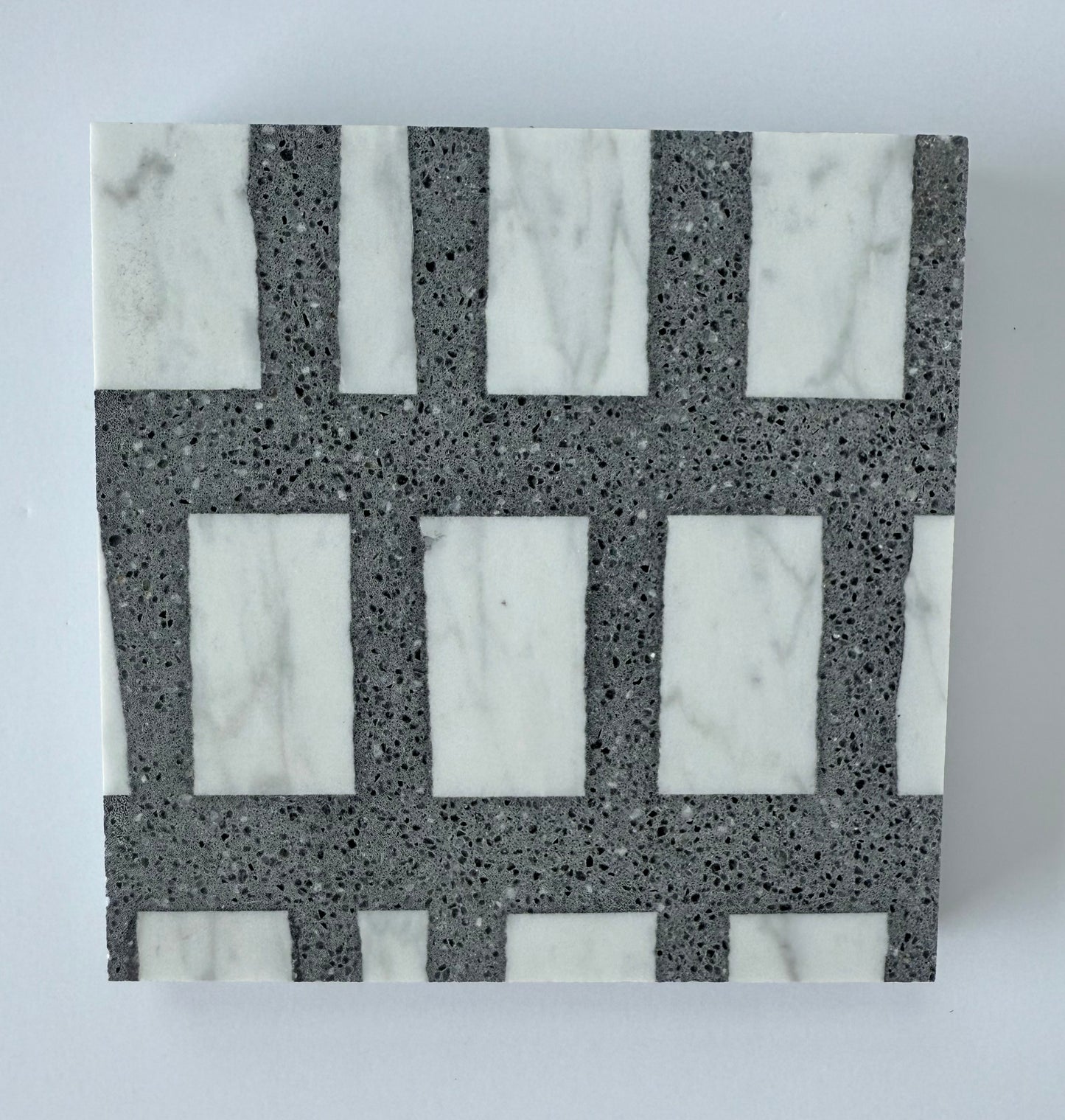 The Carlo Scarpa- Dark Gray tile by New York Cement Tile features a geometric grid in white marble and dark gray stone.