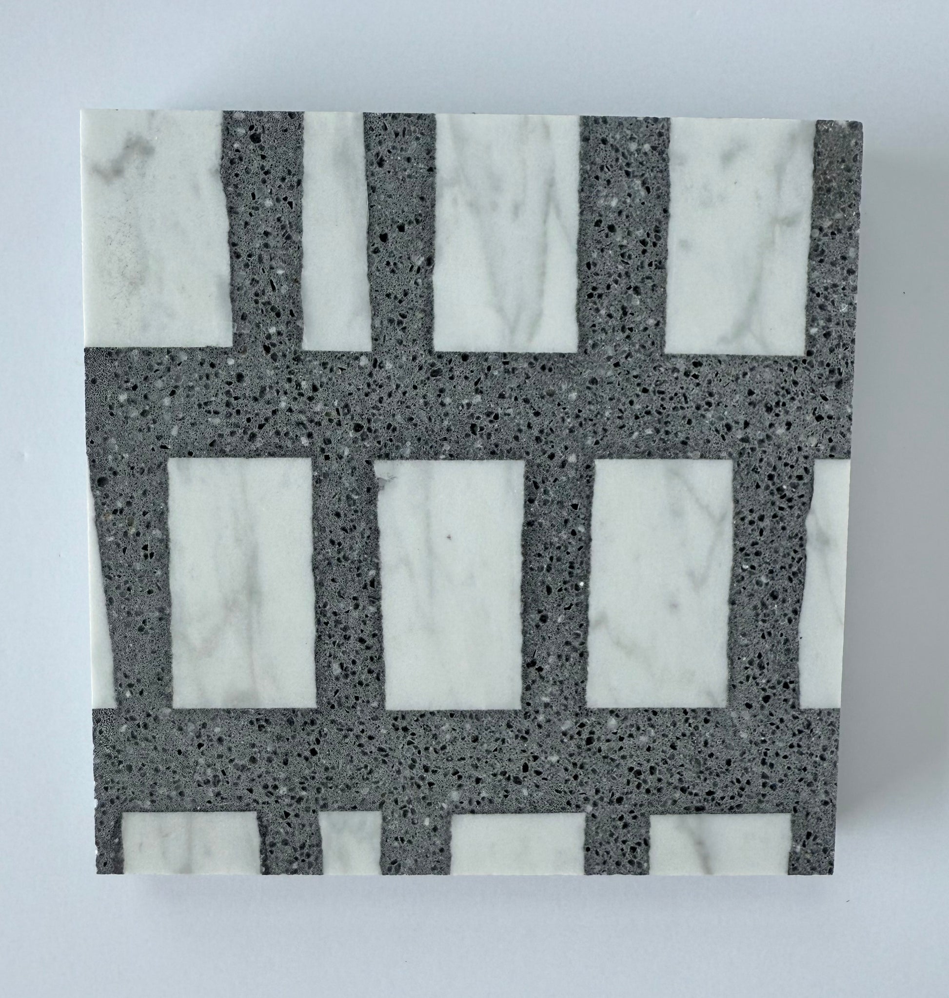 The Carlo Scarpa- Dark Gray tile by New York Cement Tile features a geometric grid in white marble and dark gray stone.