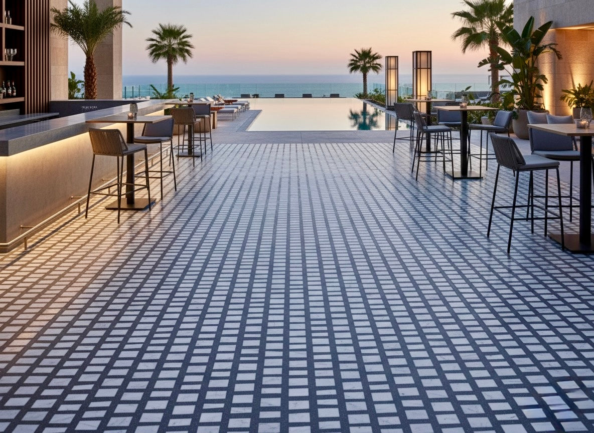 Outdoor poolside lounge with palm trees and tables, featuring Carlo Scarpa- Dark Gray tiles by New York Cement Tile.