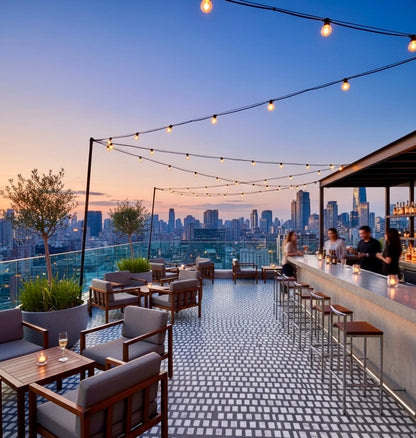 Carlo Scarpa- Dark Gray tiles by New York Cement Tile line a rooftop bar with sunset views, string lights, and city skyline.