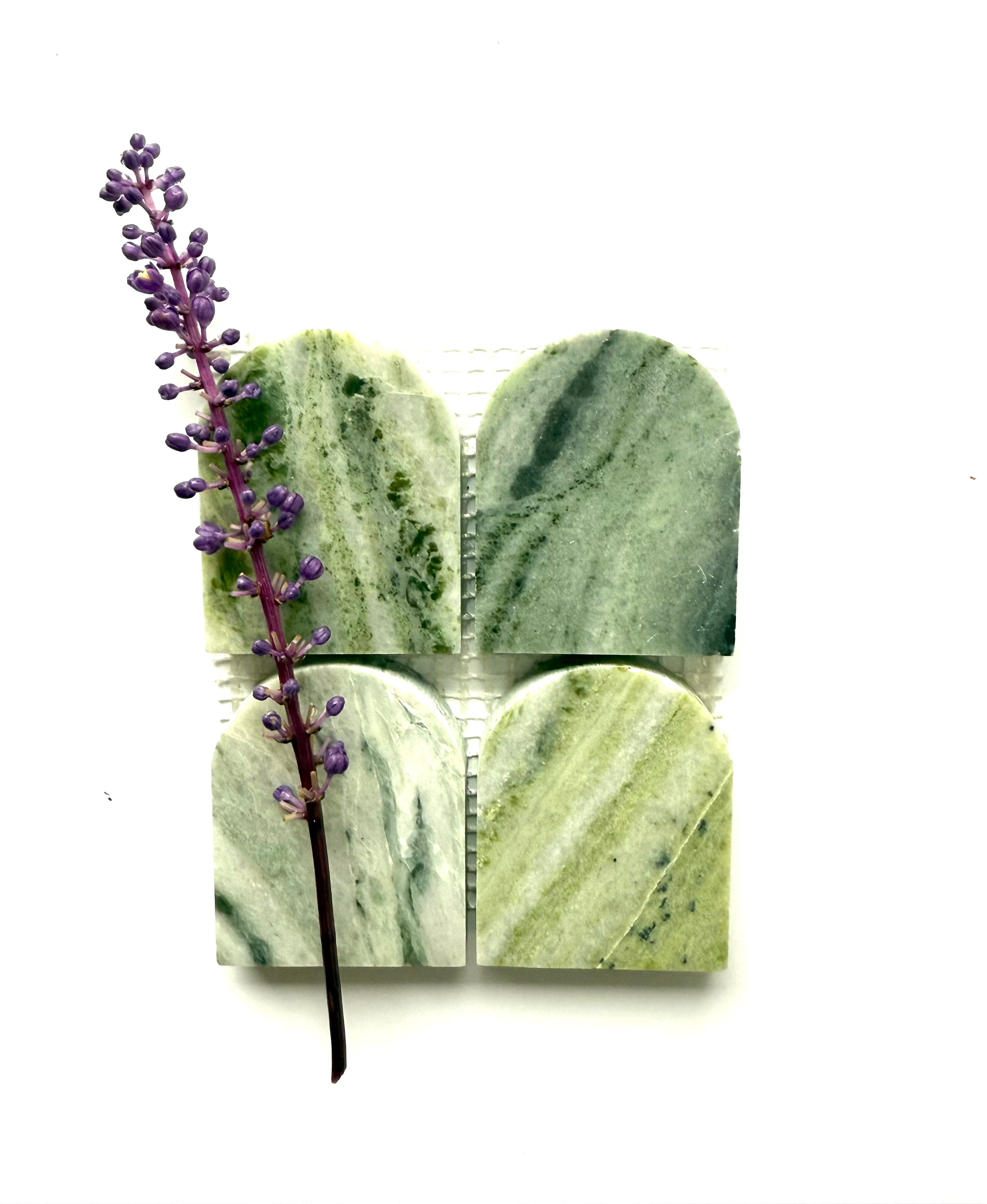 A purple flower rests on Scarpa I Green Vibes Arch Mosaic by New York Cement Tile, inspired by Italian design.