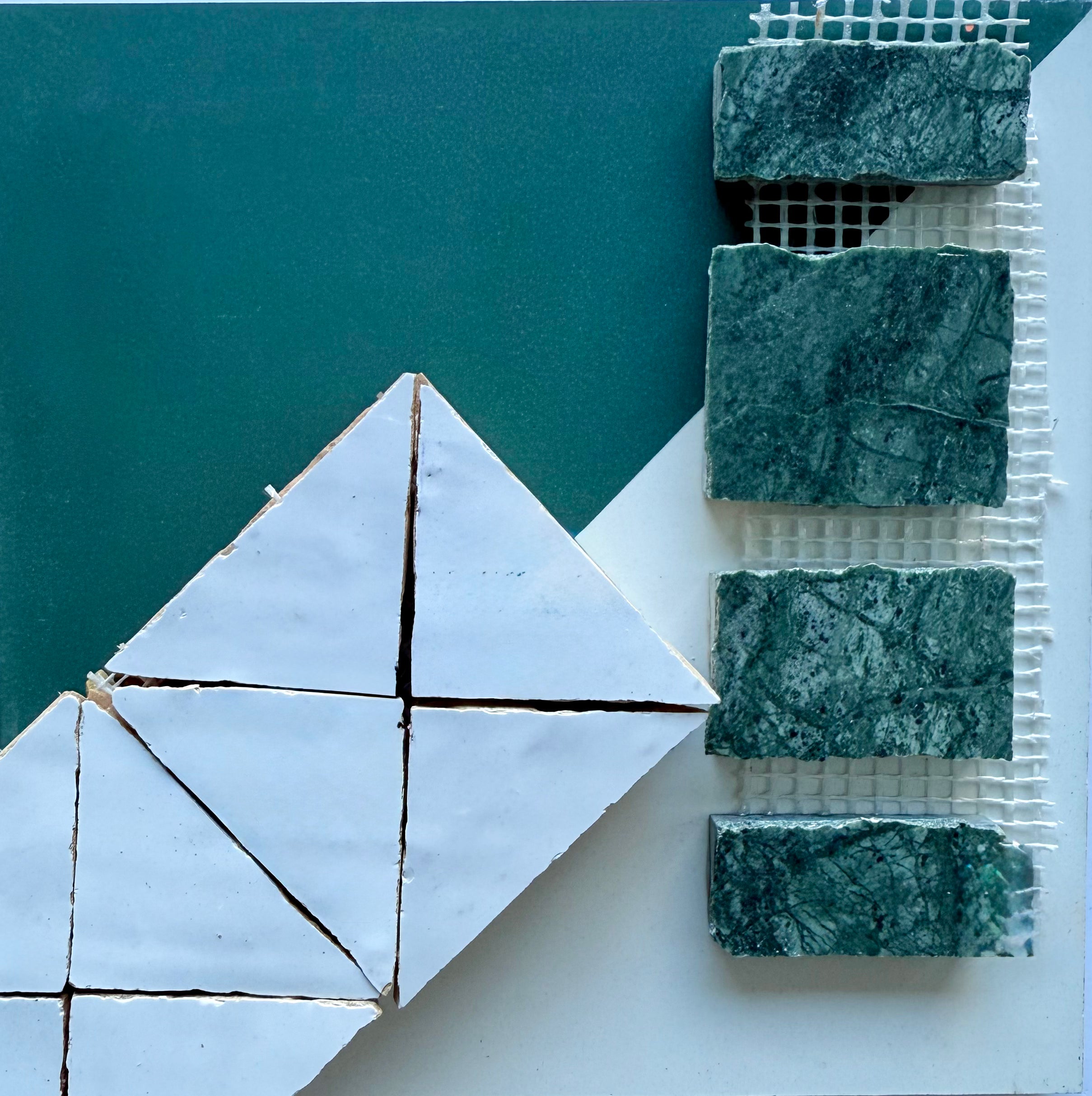 Geometric white tiles arranged diagonally next to four green marble tiles on a teal and white surface.